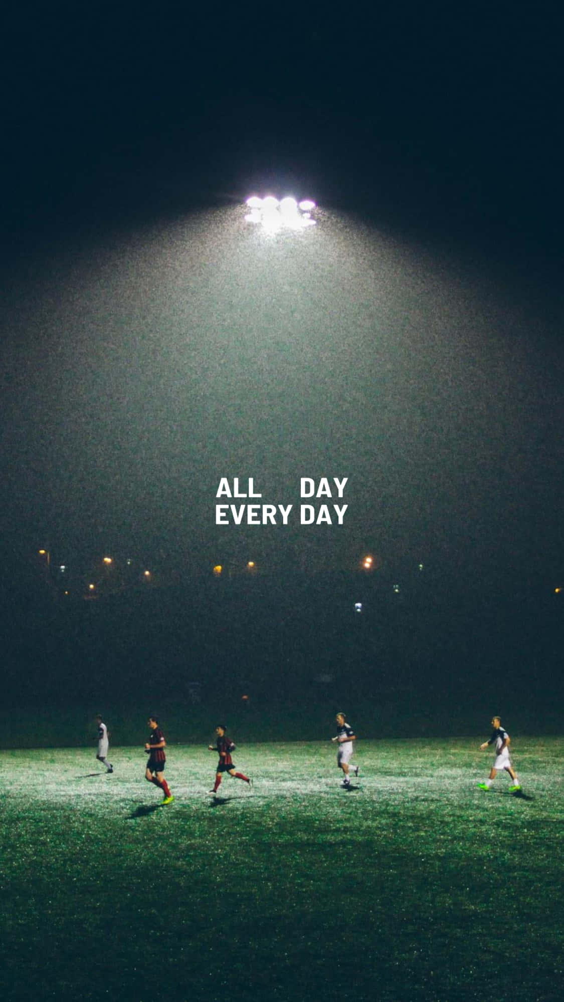 Soccer Aesthetic 桌布 壁紙 — 五名足球運動員在一個明亮的體育場燈光下，在霧氣瀰漫的夜晚場地上奔跑，遠處有城市燈光。