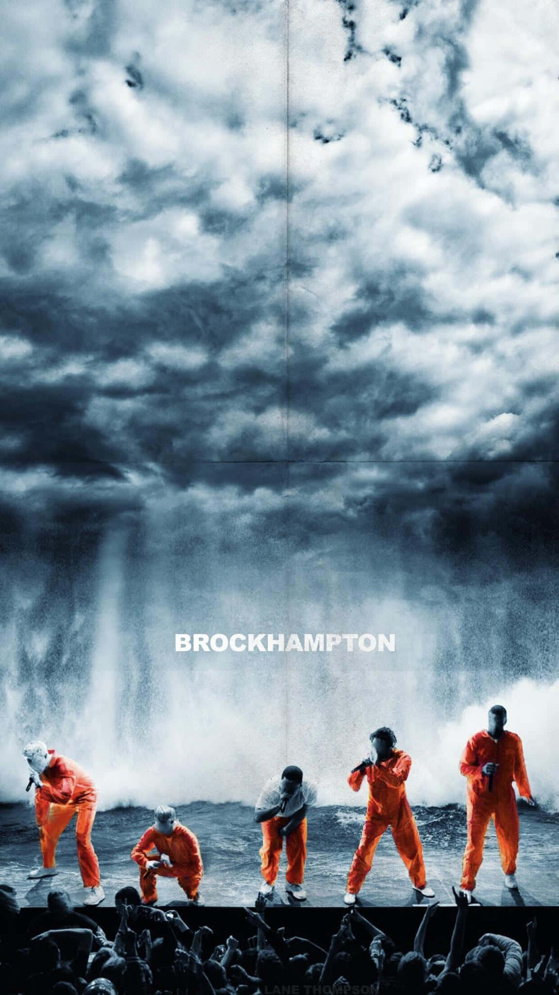 Brockhampton 桌布 壁紙 — 五名身穿橙色連身衣的男子在暴風雨海洋舞台上表演，天空陰暗多雲，下方有群眾。