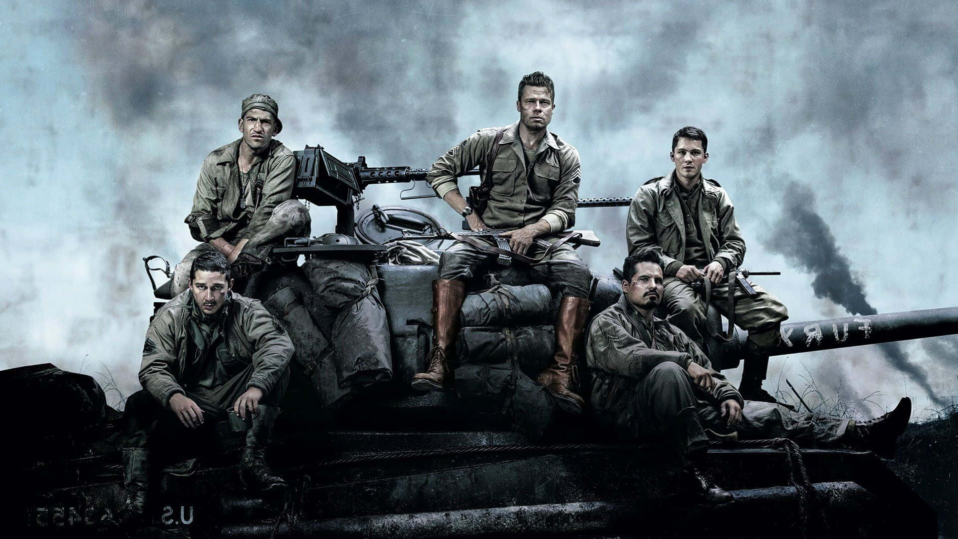 fury 桌布 壁紙 — 五名身穿泥濘軍裝的疲憊士兵坐在一輛佈滿戰痕的坦克上，背景是煙霧瀰漫的灰色戰場天空。
