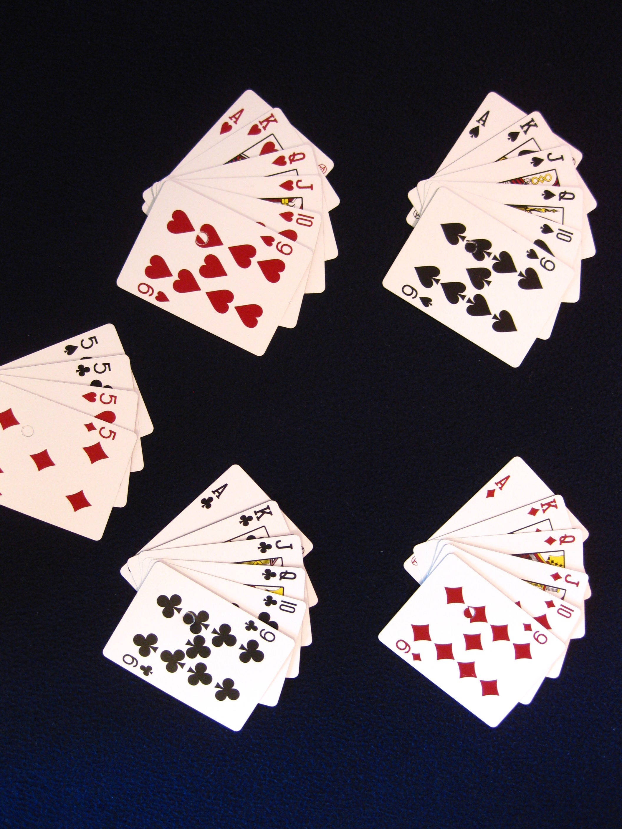 Casino 桌布 壁紙 — 五手扇形撲克牌散佈在深藍色表面上，顯示所有四種花色和各種點數。