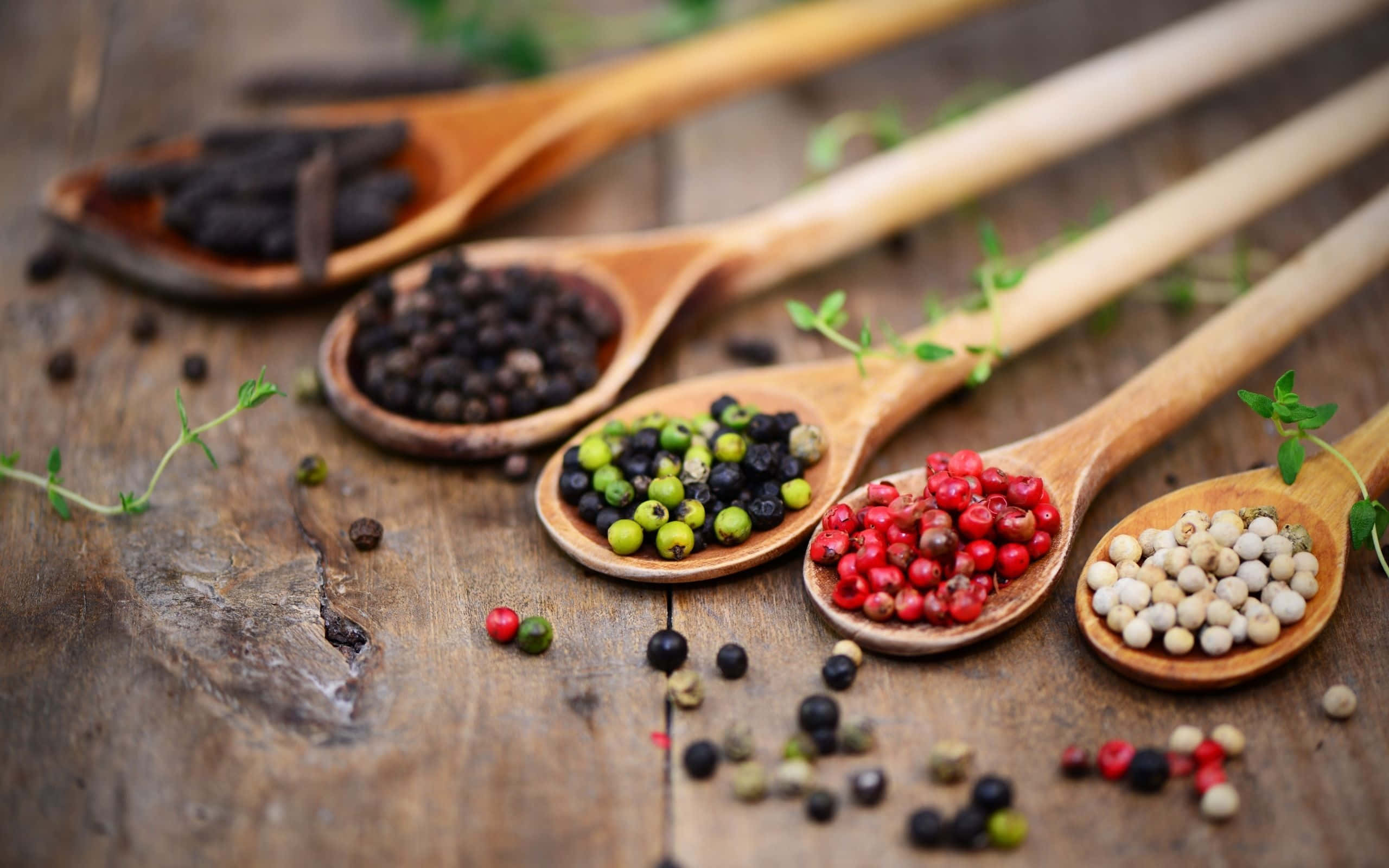 Spice 桌布 壁紙 — 五把木匙盛載著各式胡椒粒和新鮮百里香，置於鄉村風格的木質表面上。