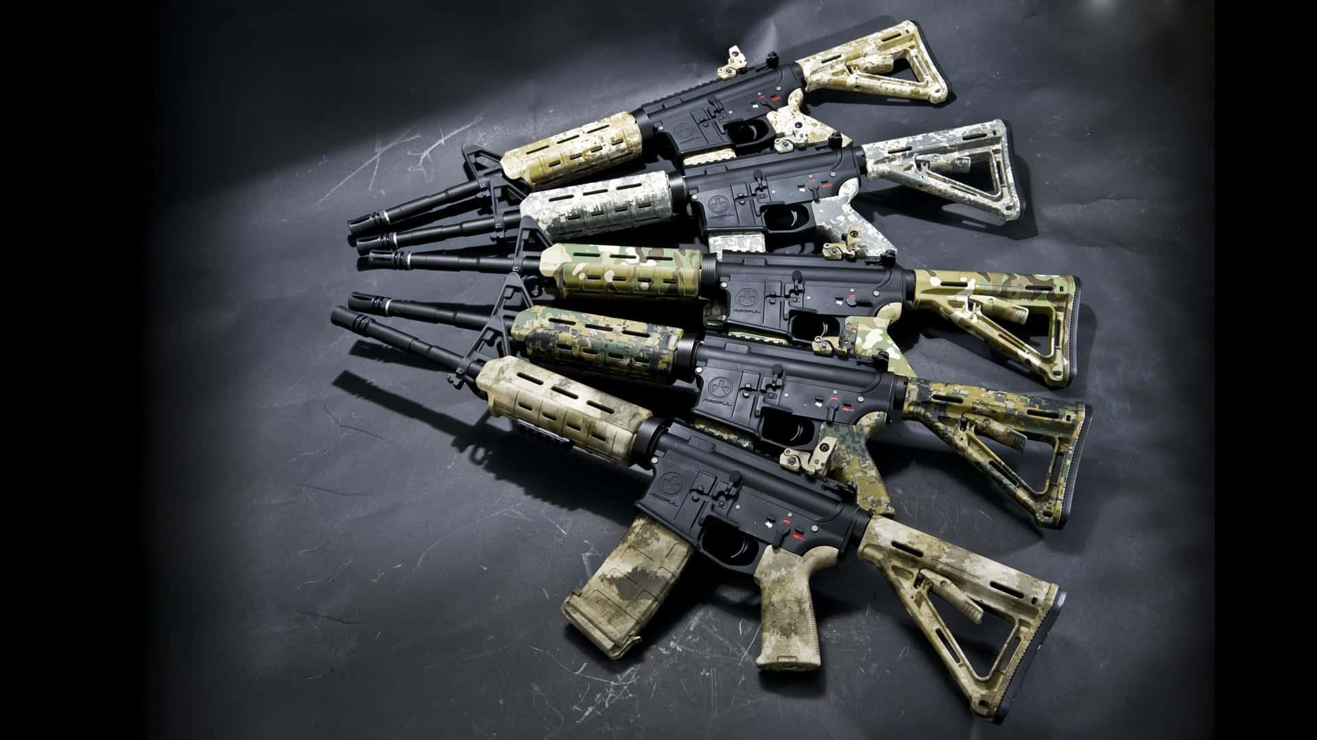 Rifle 桌布 壁紙 — 五把迷彩圖案突擊步槍以扇形排列在深色紋理表面上，在戲劇性的聚光燈下。