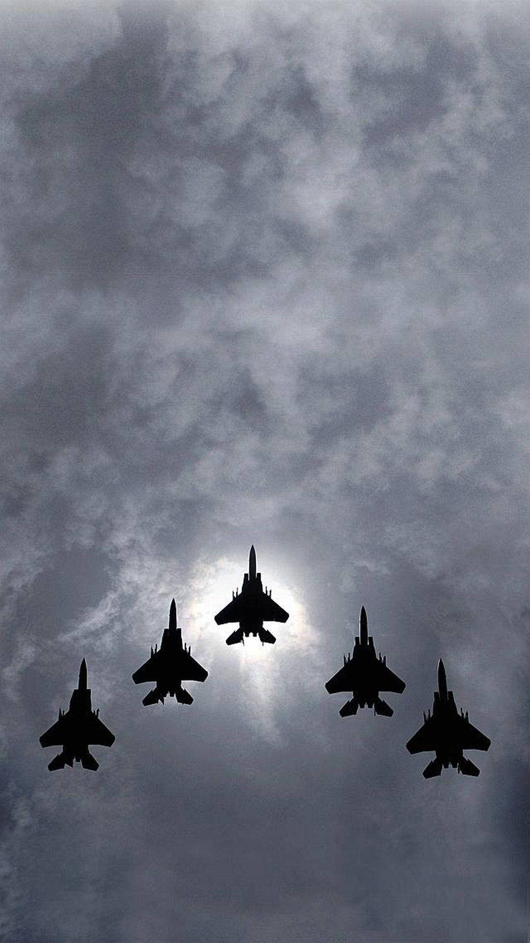 Military Jets 桌布 壁紙 — 五架戰鬥機在戲劇性的多雲天空中緊密編隊飛行，太陽在它們身後發光。