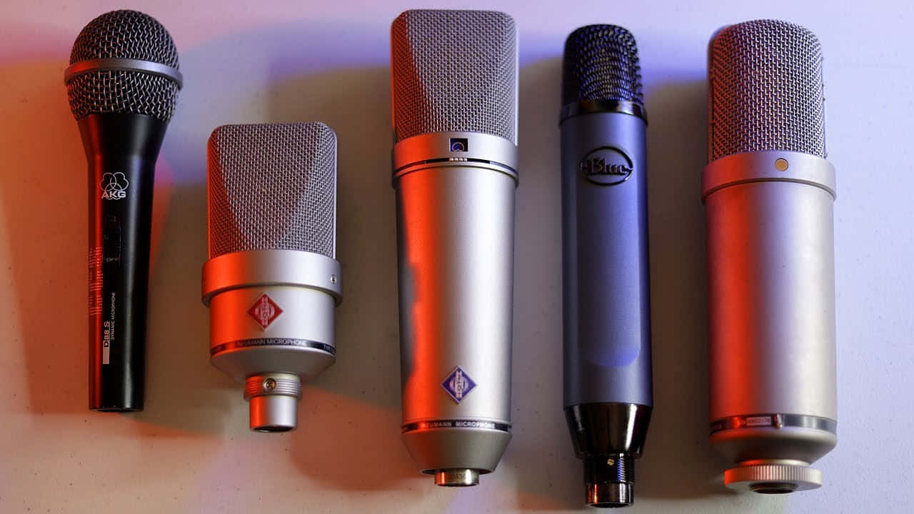 Microphones 桌布 壁紙 — 五款不同設計和顏色的專業錄音室麥克風整齊地排列在柔和照明的表面上。