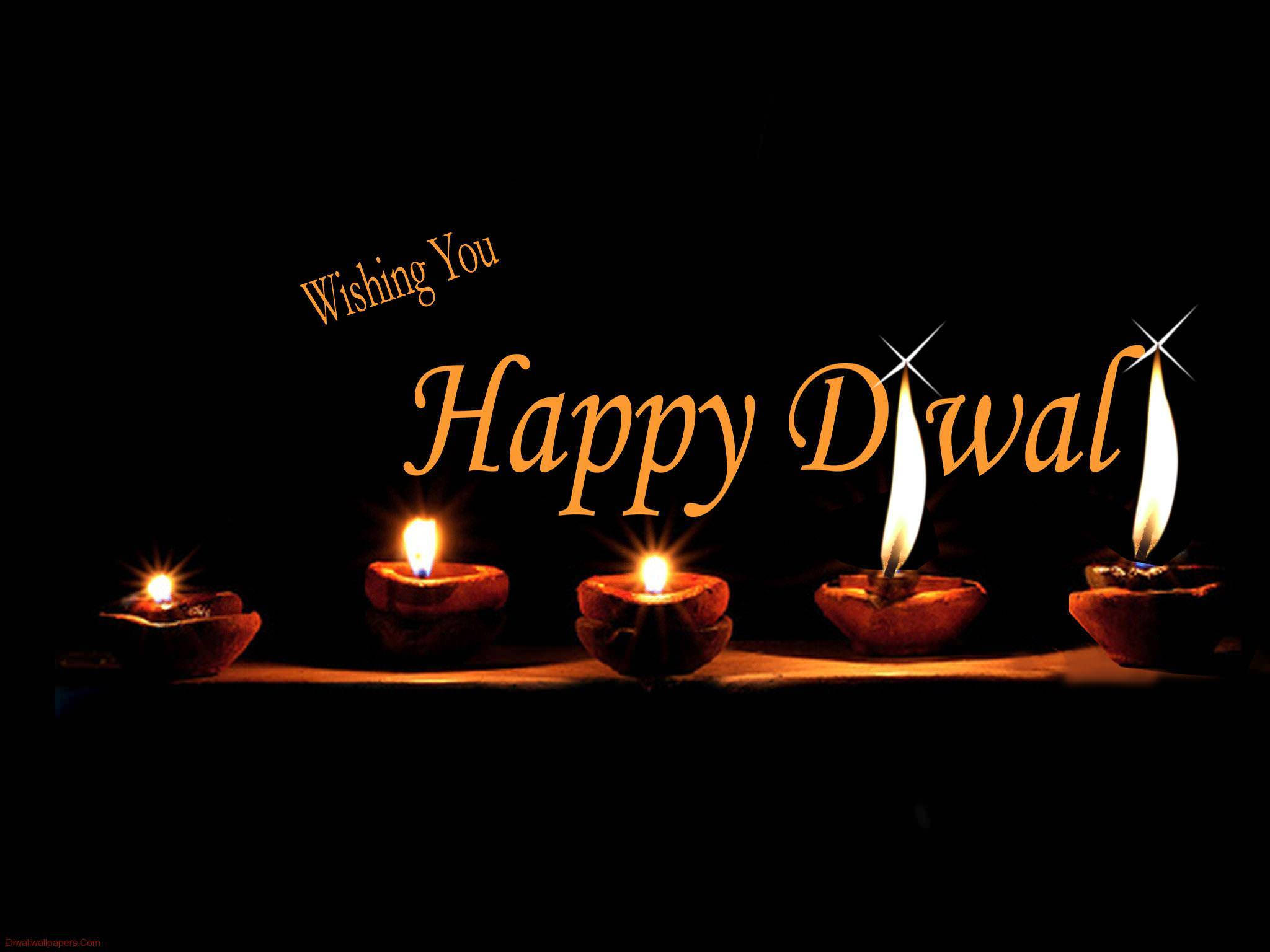 Happy Diwali 桌布 壁紙 — 五盞發光的油燈在黑色背景上投射溫暖光線，並帶有金色「Happy Diwali」文字。