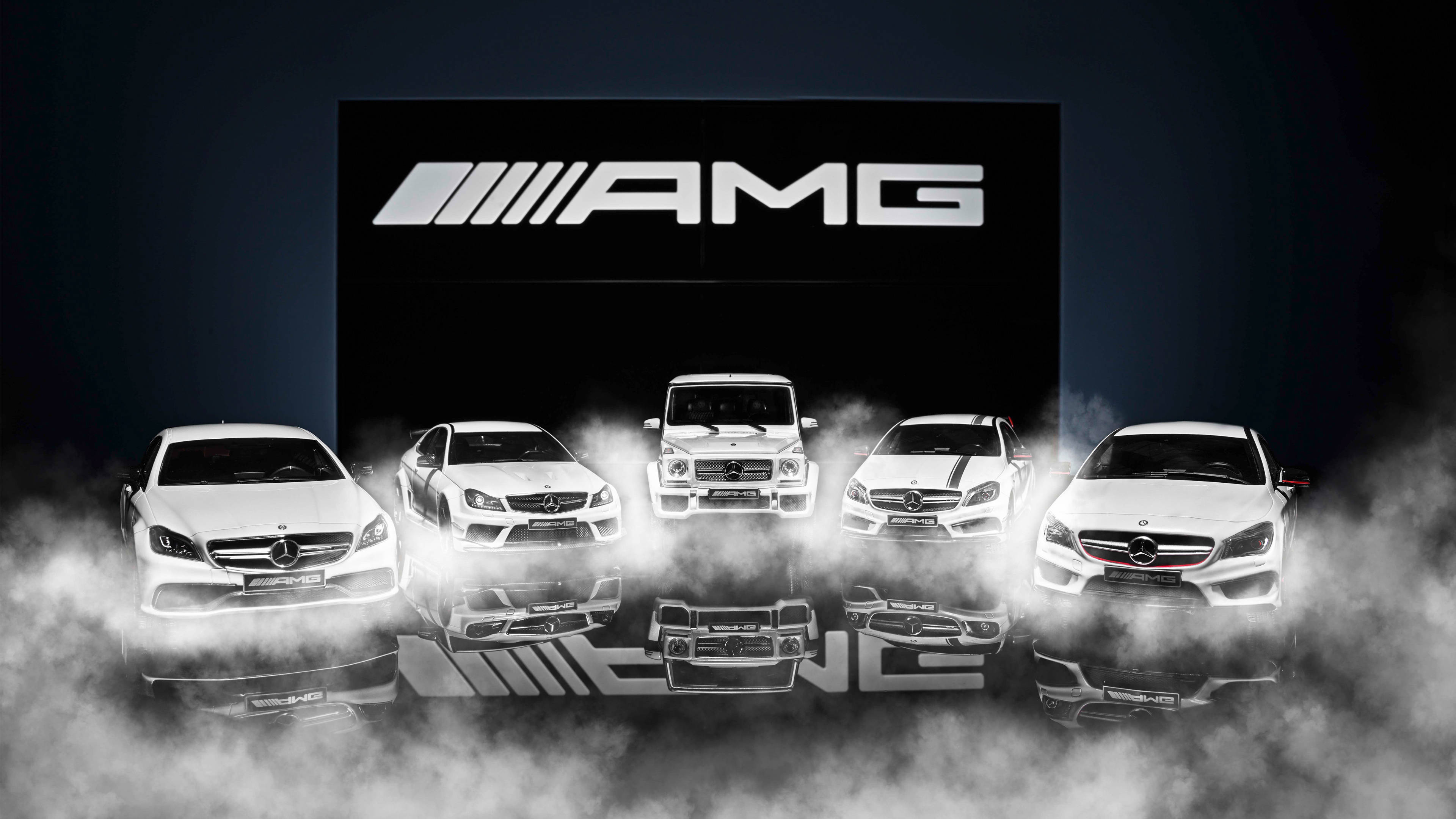 Amg 桌布 壁紙 — 五輛白色AMG汽車在黑暗的攝影棚環境中，從煙霧中浮現，上方有發光的AMG標誌。