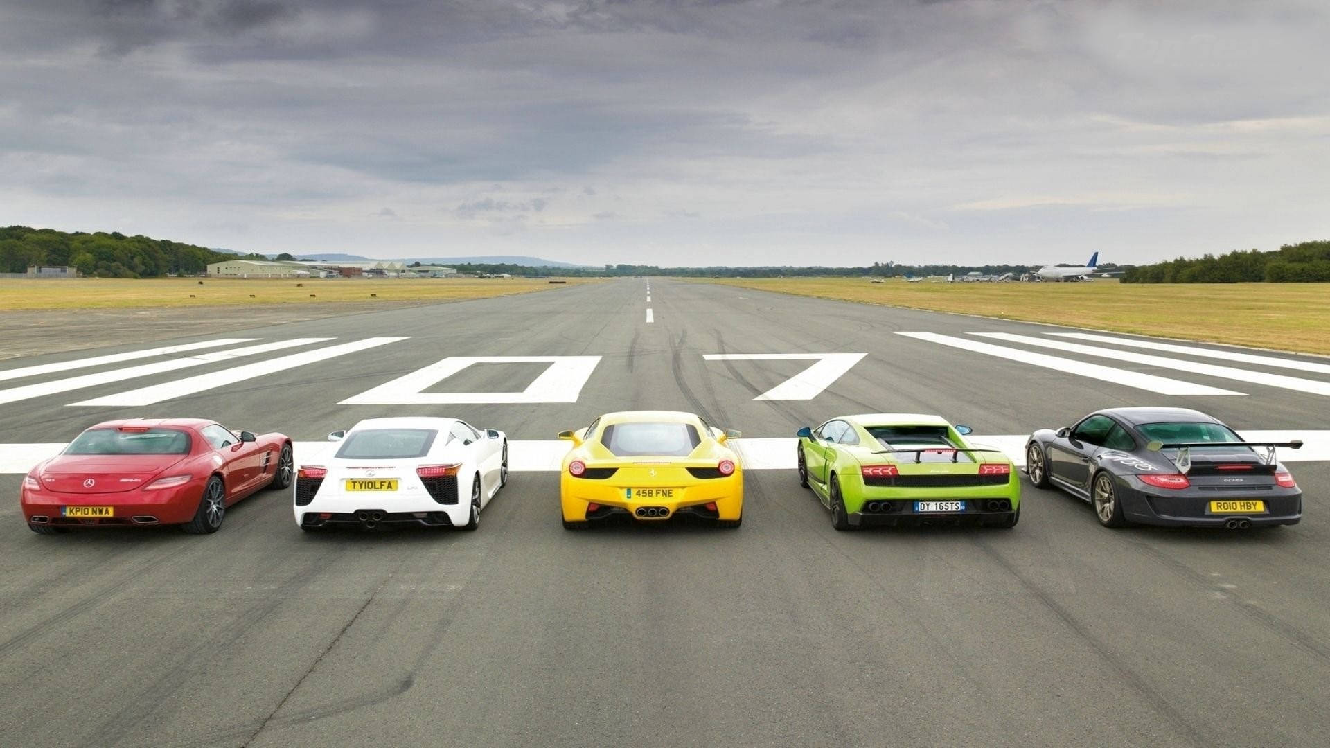 Runway 桌布 壁紙 — 五輛高性能跑車，分別為紅色、白色、黃色、綠色和黑色，在多雲的天空下排列在跑道上。