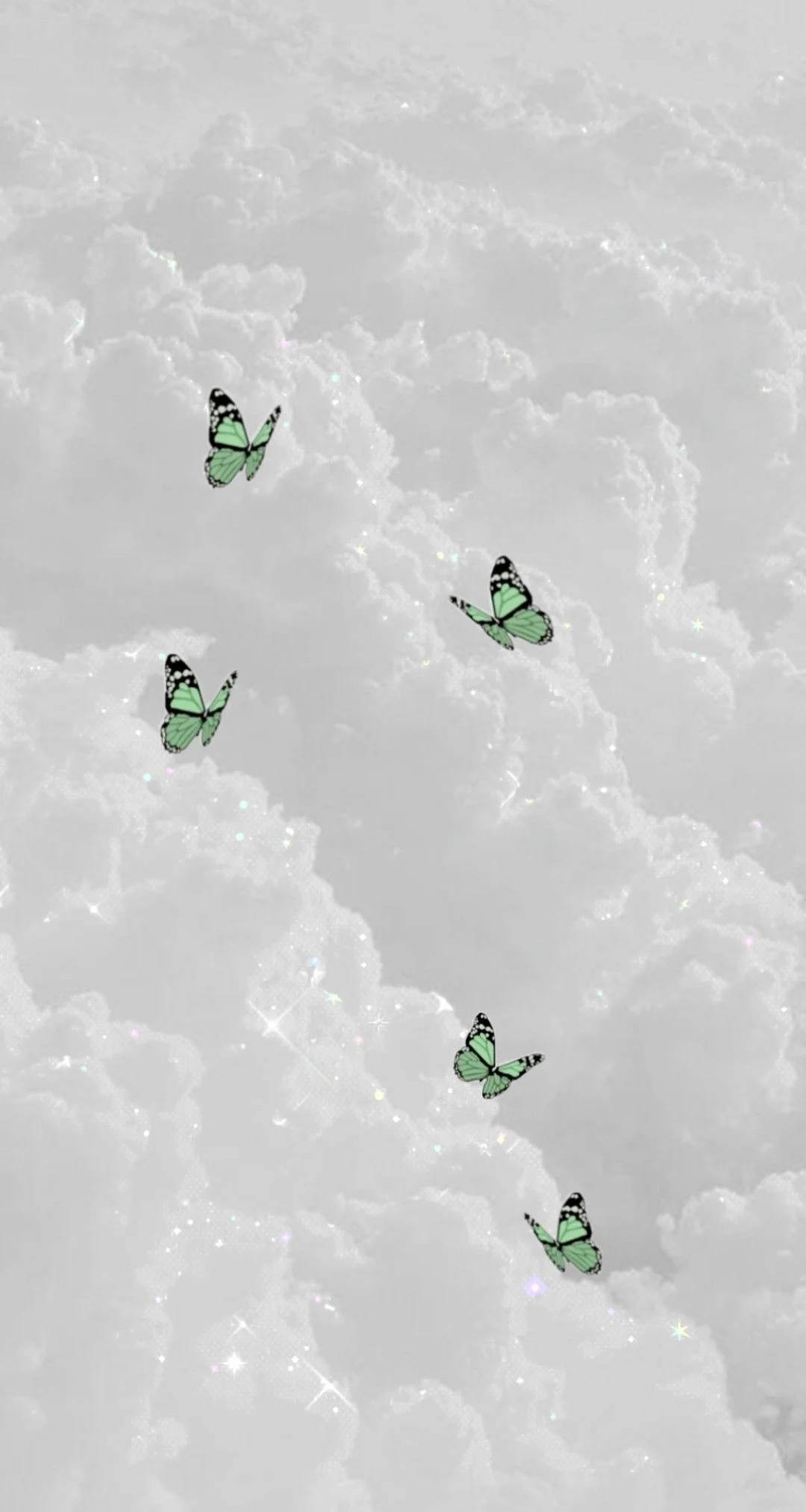 Butterflies 桌布 壁紙 — 五隻發光的綠色蝴蝶在點綴著閃爍光芒的柔和白色雲景中優雅地翩翩起舞。