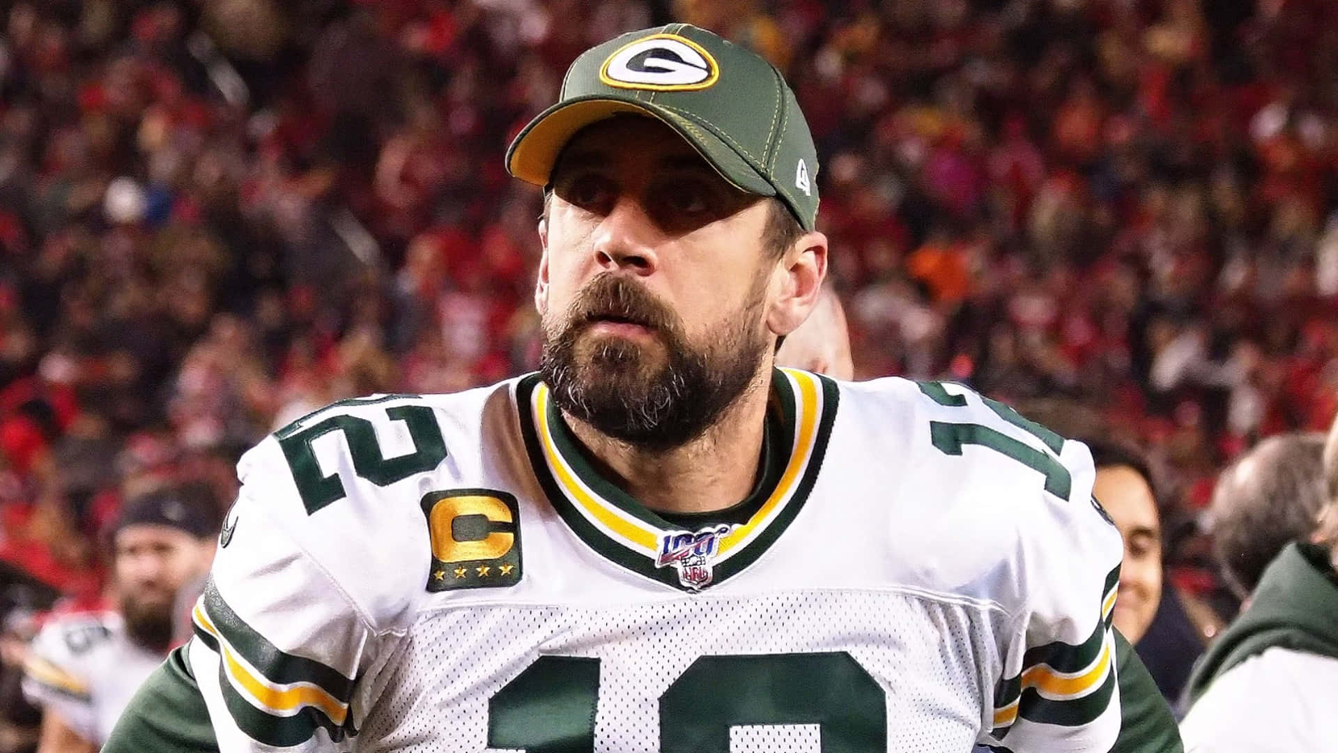 Aaron Rodgers 桌布 壁紙 — 亞倫·羅傑斯身穿綠灣包裝工隊球衣的近距離特寫，在夜間足球比賽中表情專注。