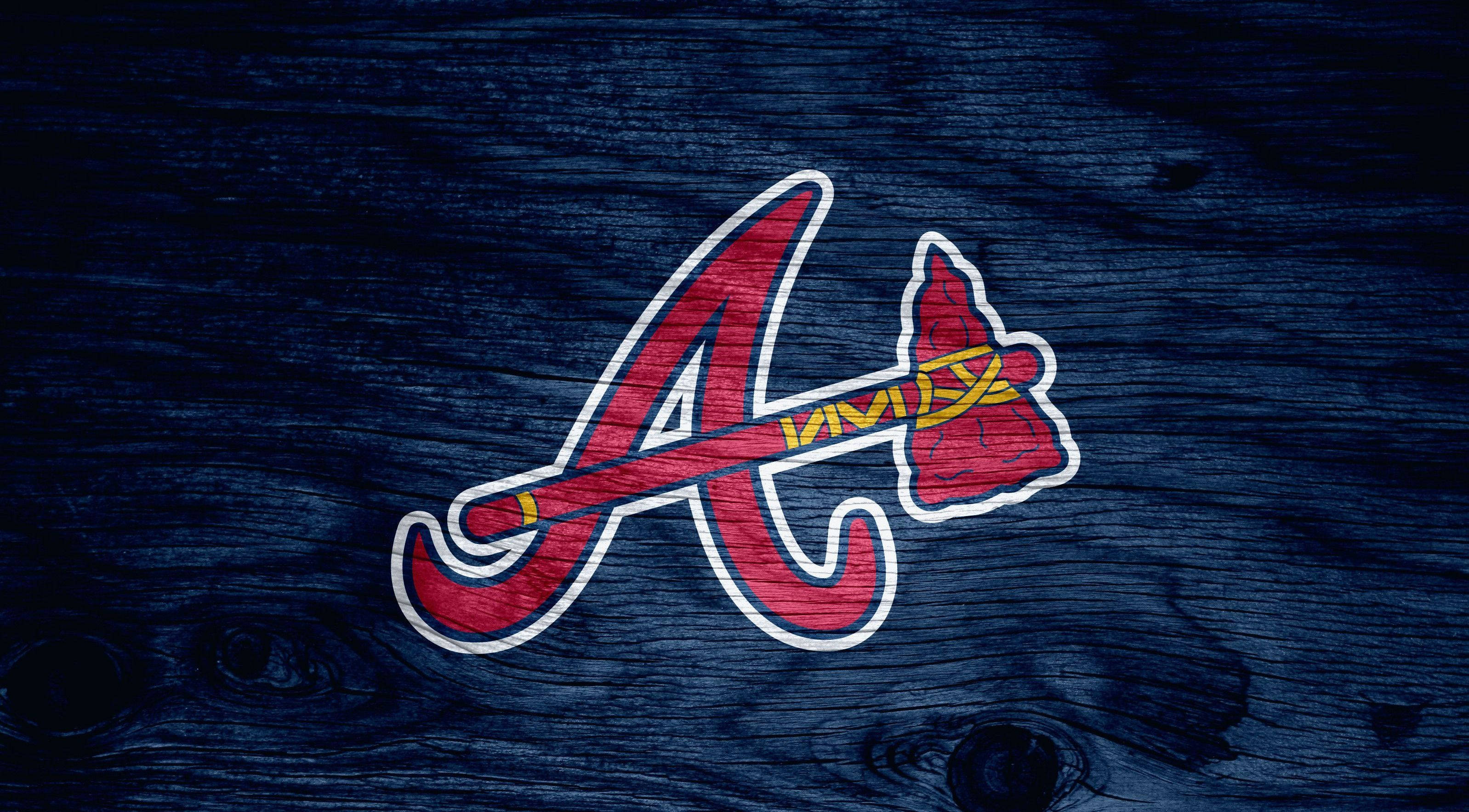 Braves 桌布 壁紙 — 亞特蘭大勇士隊標誌，紅金色配白色輪廓，置於深藍色風化木紋理上。