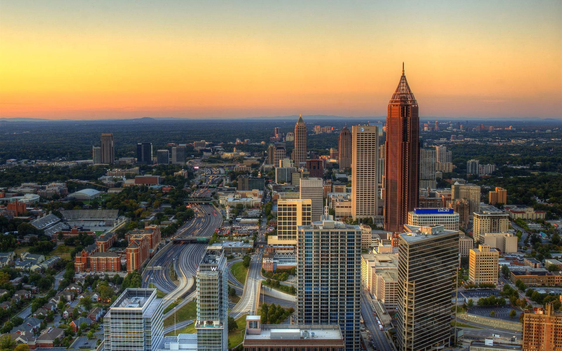 Atlanta 桌布 壁紙 — 亞特蘭大天際線的鳥瞰圖，夕陽金色光芒灑滿摩天大樓和蜿蜒的高速公路。