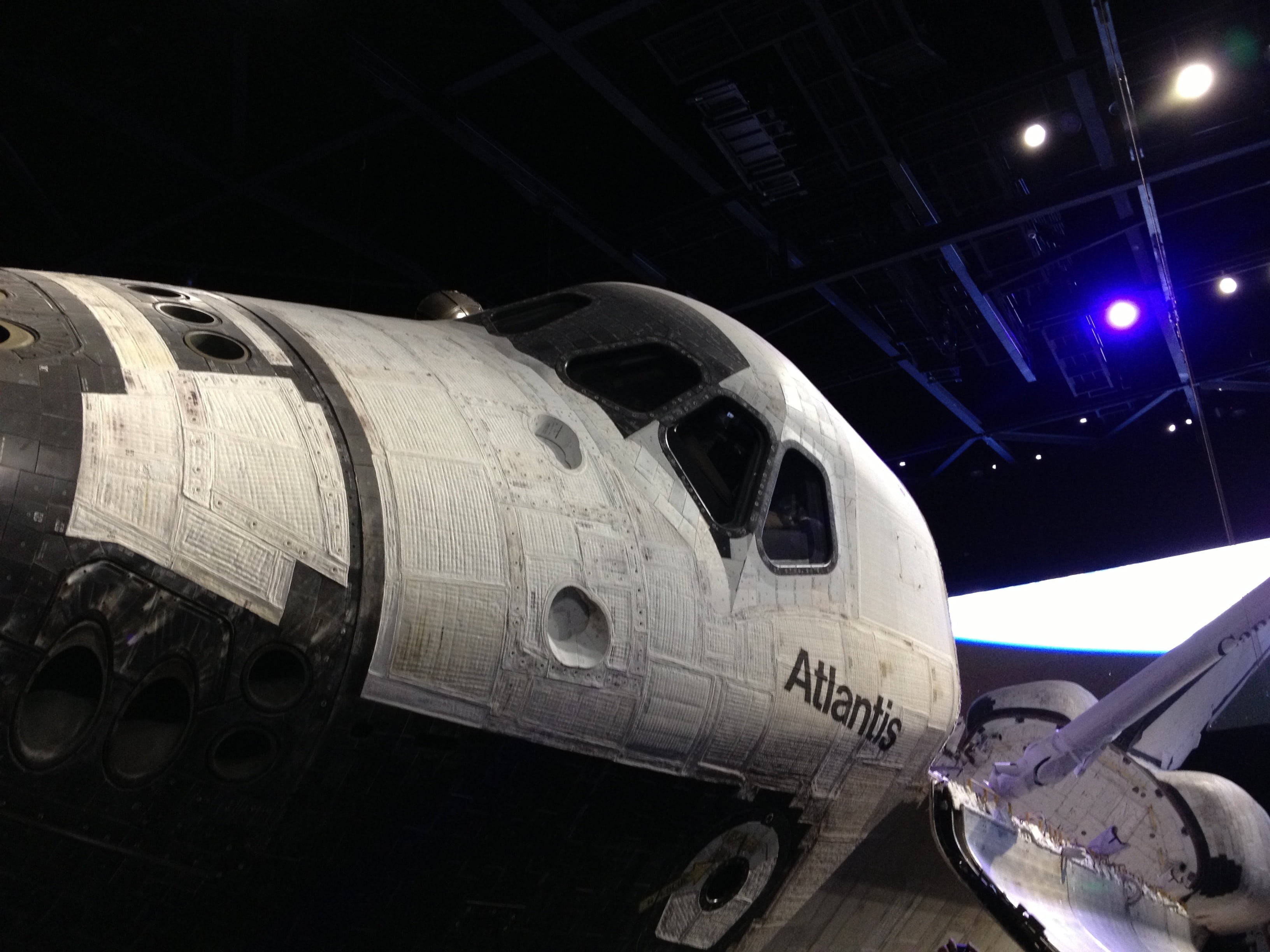 Nasa 桌布 壁紙 — 亞特蘭提斯號太空梭在燈光昏暗的博物館中展出，藍色聚光燈凸顯其風化的白色和黑色外觀。