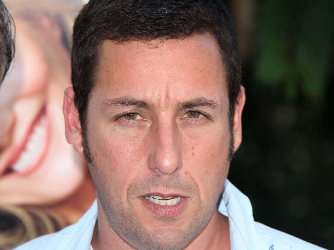 Adam Sandler 桌布 壁紙 — 亞當·山德勒的近距離肖像，直視鏡頭，面帶微笑，身穿淺藍色襯衫。