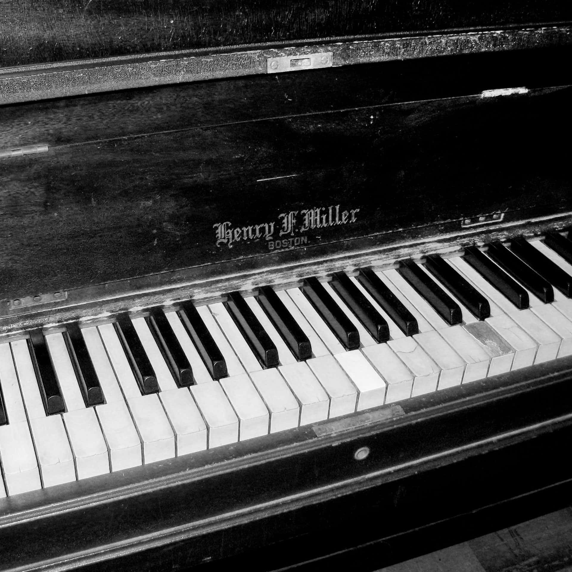 Black And White Piano 桌布 壁紙 — 亨利·F·米勒復古鋼琴鍵盤的特寫黑白照片，顯示磨損的琴鍵和陳舊的木頭。