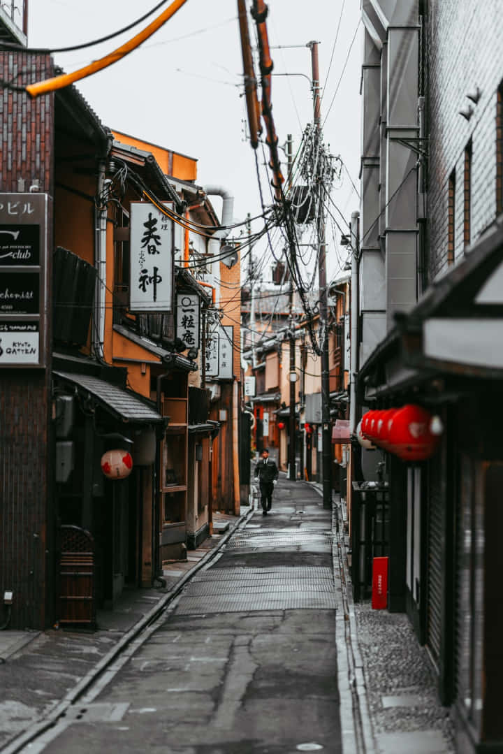 平靜 桌布 壁紙 — 京都一條狹窄的雨巷，兩旁是傳統木建築和懸掛的紅燈籠，天空陰沉。