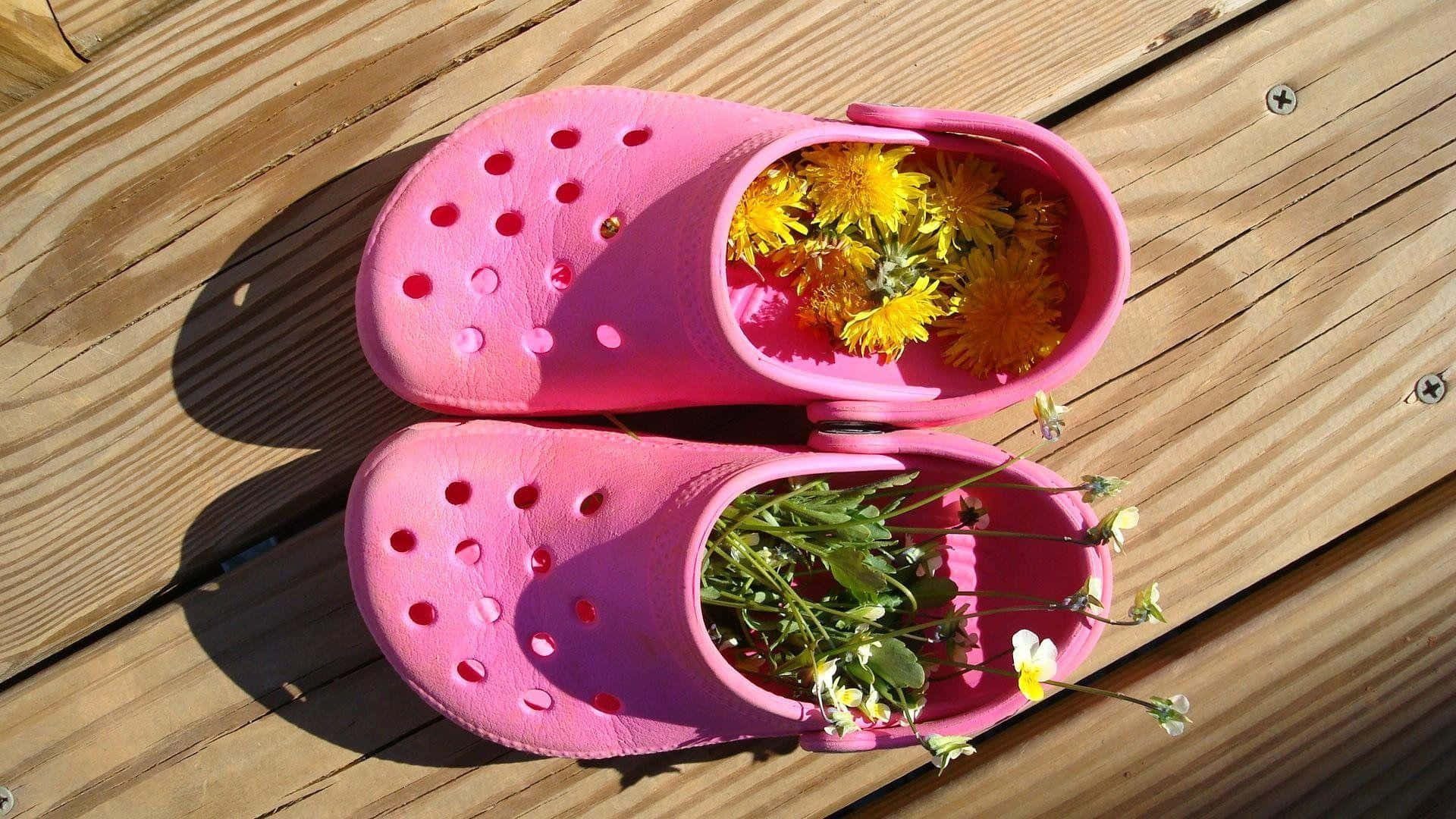 Crocs 桌布 壁紙 — 亮粉紅色木屐裝滿黃色蒲公英和白色花朵，放在陽光普照的木甲板上。