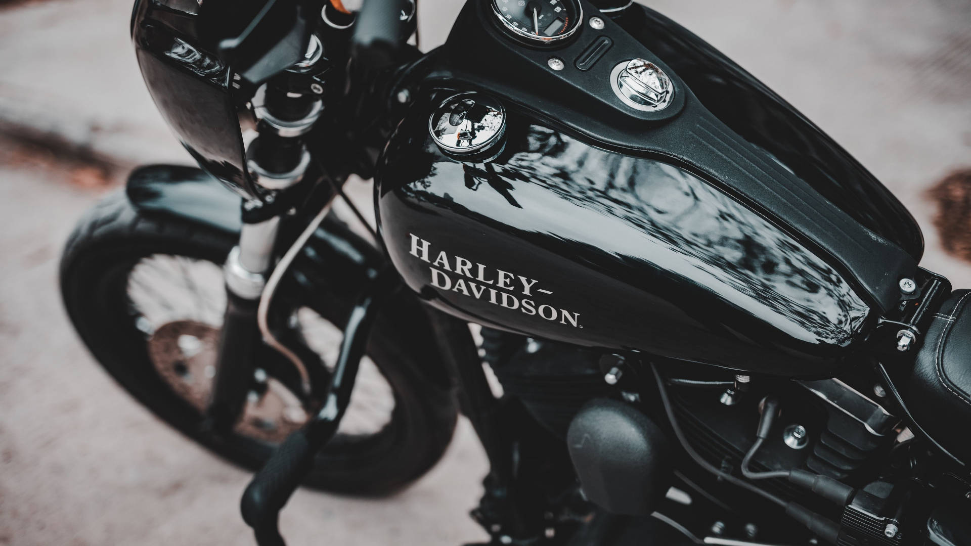 機車 桌布 壁紙 — 亮面黑色Harley-Davidson機車油箱特寫，反射樹木和天空，帶有鍍鉻裝飾。