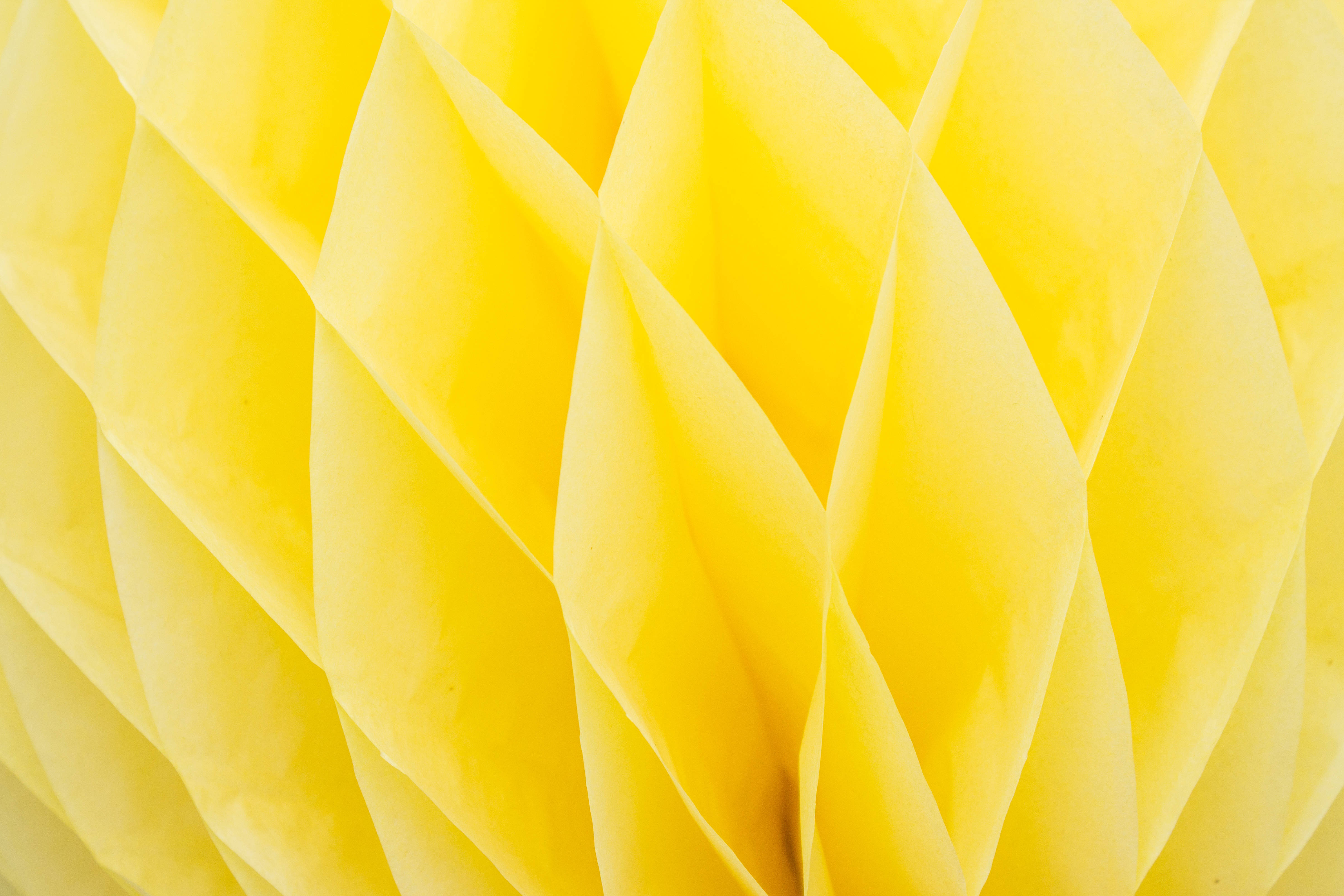 the yellow 桌布 壁紙 — 亮黃色蜂窩紙裝飾的特寫，帶有柔軟的摺痕和柔和的陰影。