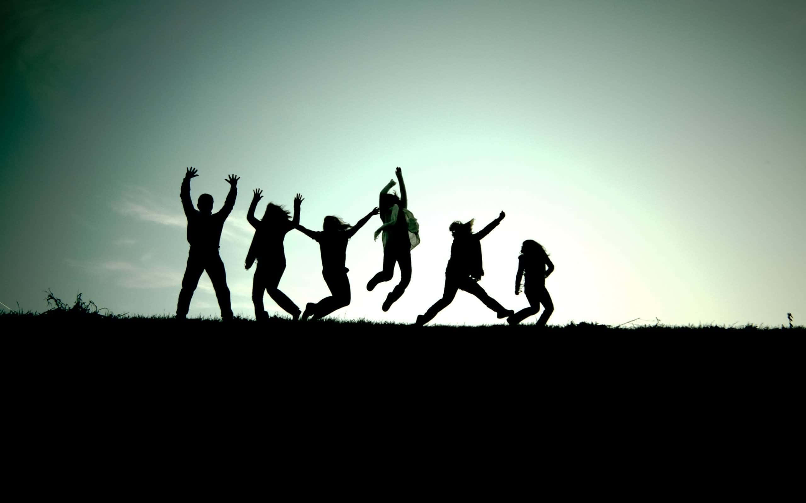 人們在山丘上跳躍的剪影 壁紙
