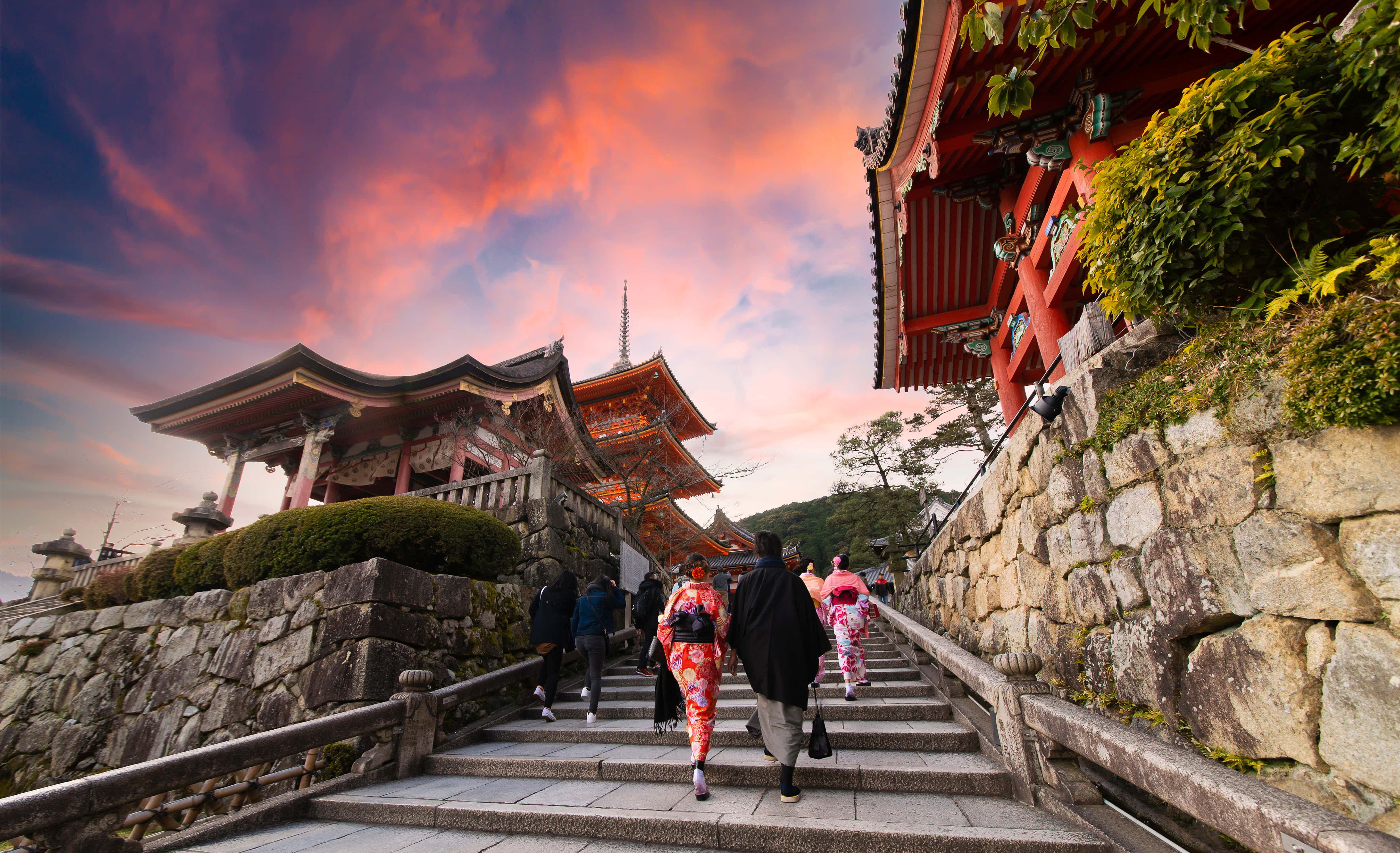 日式 桌布 壁紙 — 人們在火紅的夕陽天空下，登上通往傳統日本寺廟建築的石階。