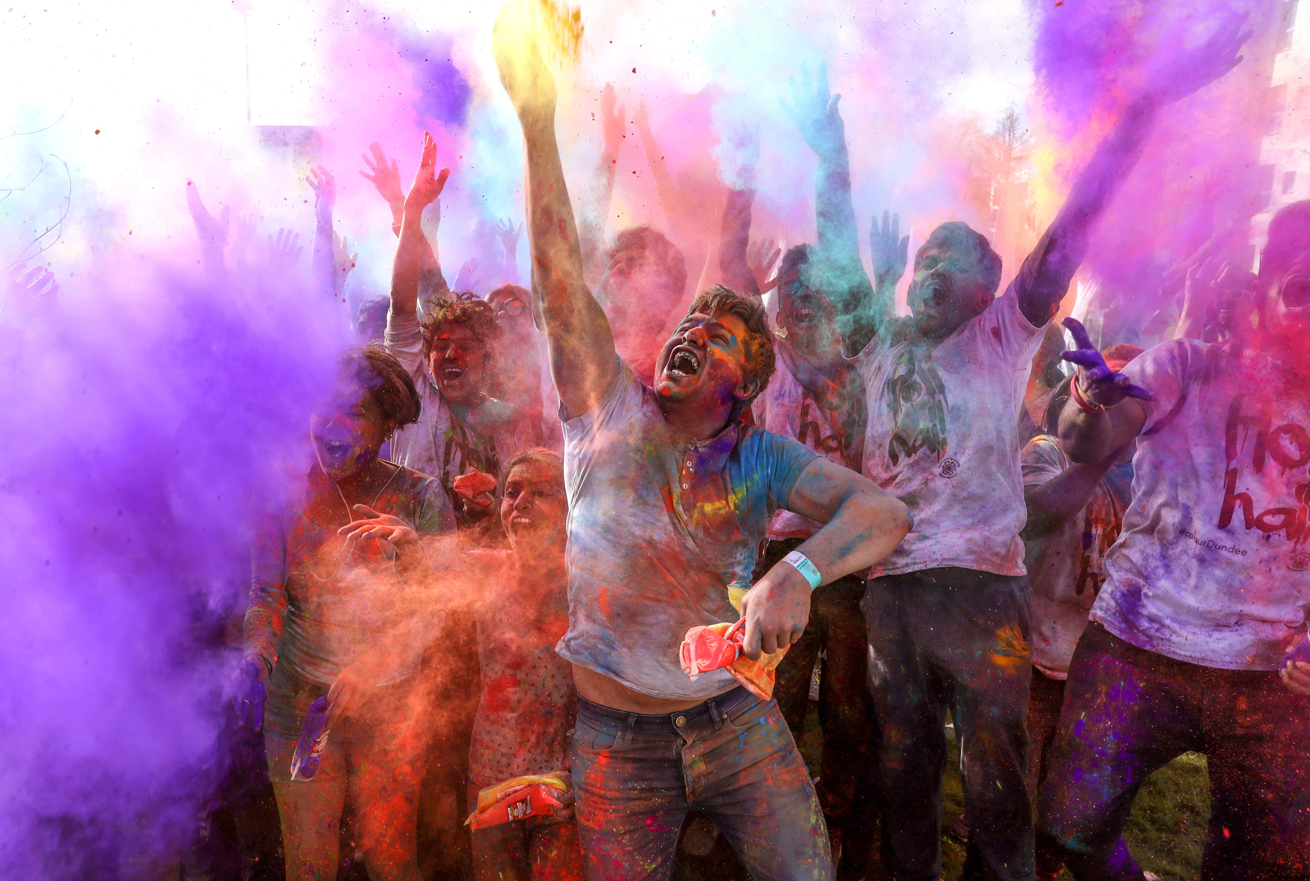 Holi 桌布 壁紙 — 人們在熱鬧的節日慶祝活動中，歡快地將鮮豔的彩色粉末拋向空中。