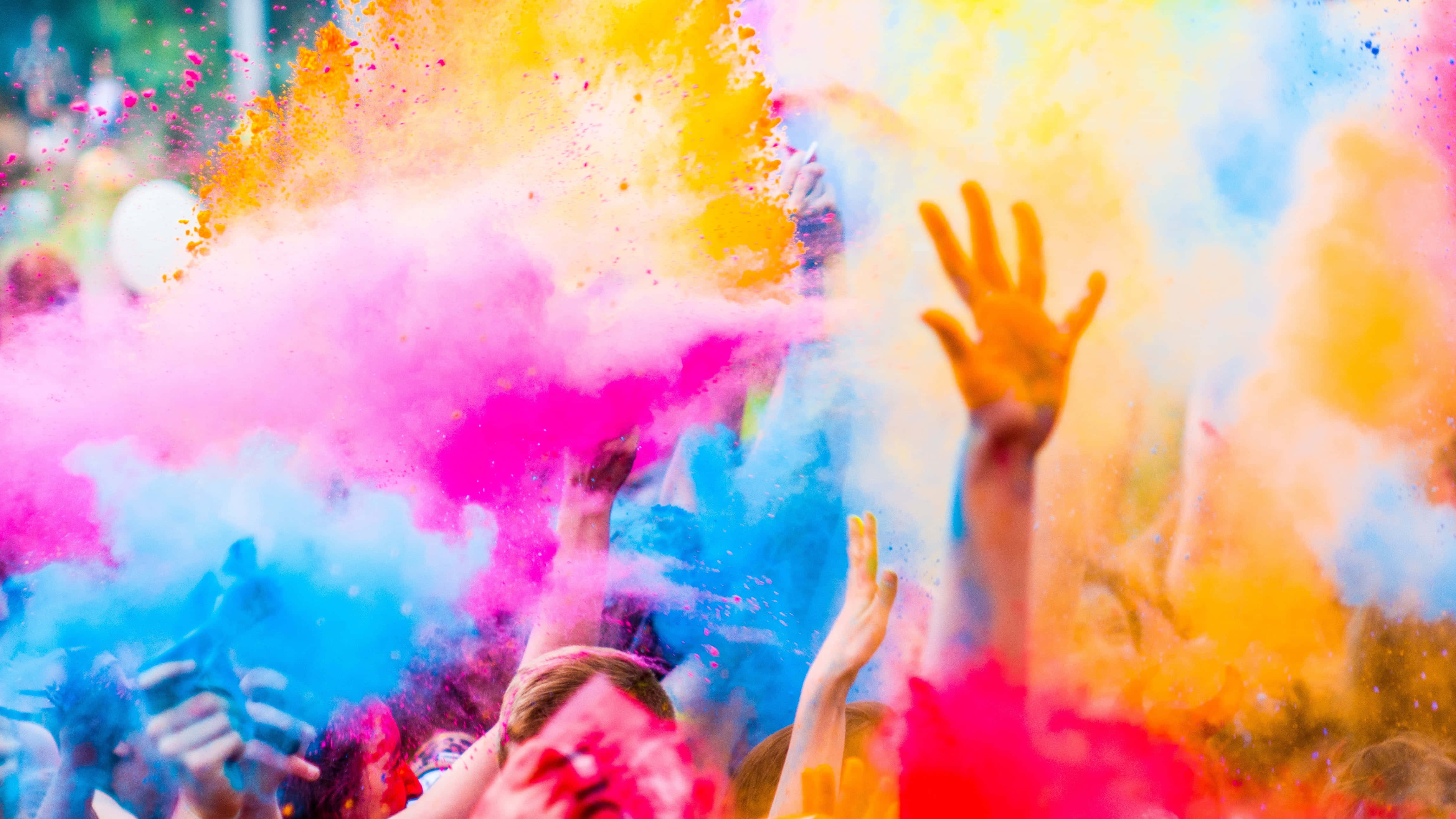 Holi 桌布 壁紙 — 人們在節日慶祝活動中歡樂地將鮮豔的彩色粉末拋向空中。