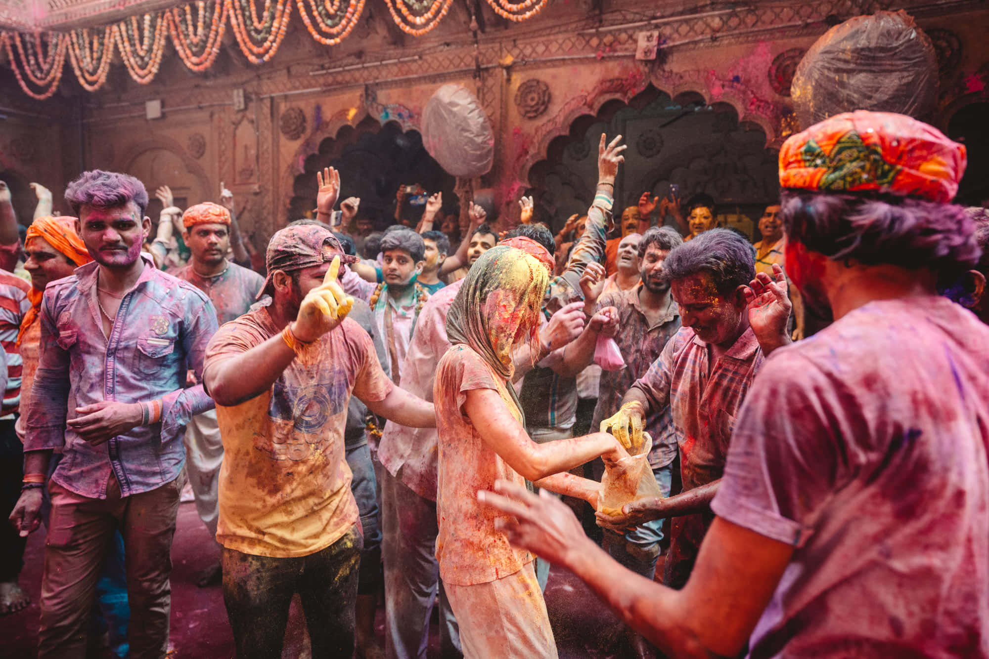 Holi 桌布 壁紙 — 人們在裝飾華麗的寺廟庭院中，在侯麗節期間歡樂地拋灑彩色粉末。