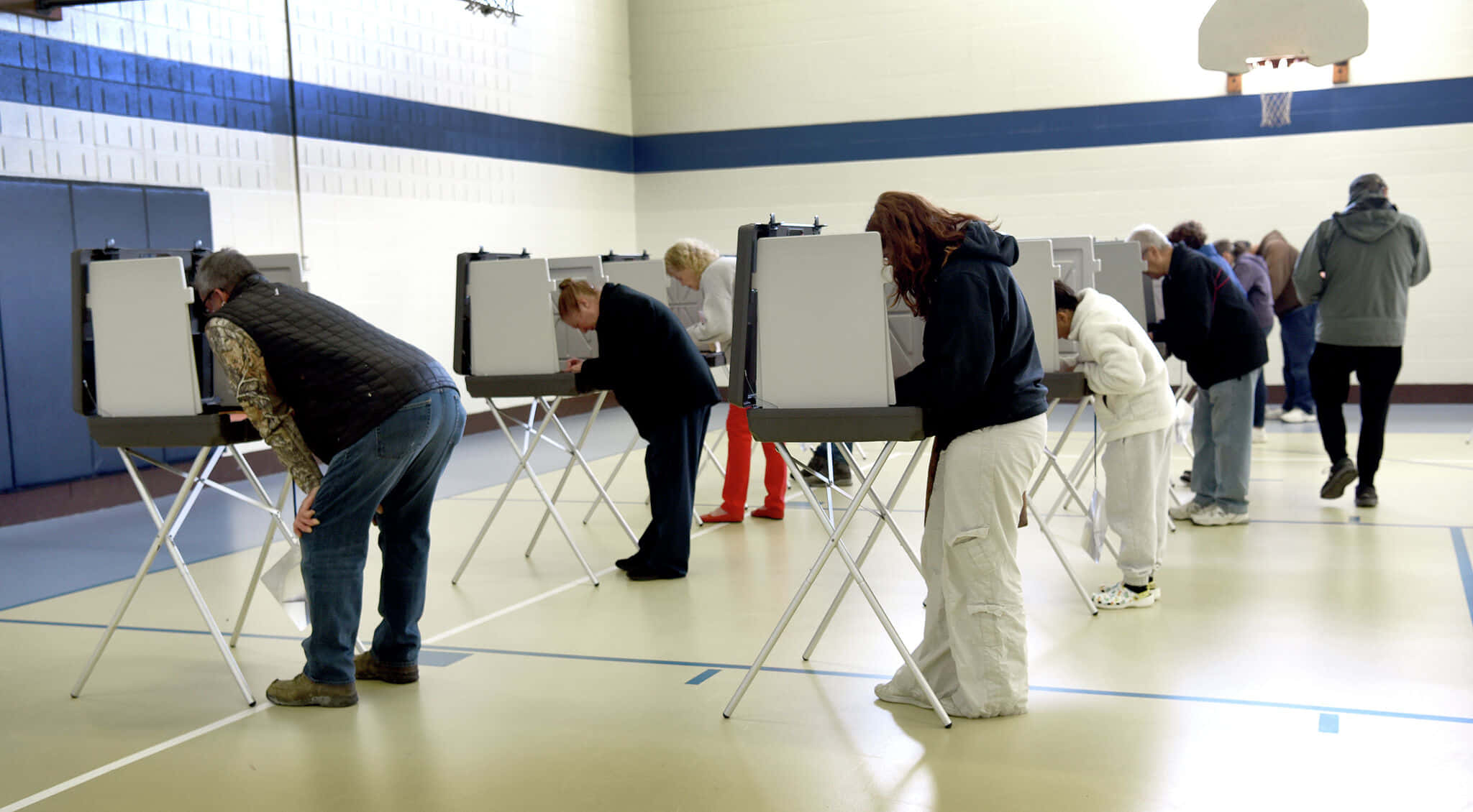 Voting 桌布 壁紙 — 人們在設有藍白牆壁和籃球架的體育館內的流動投票亭中私下投票。