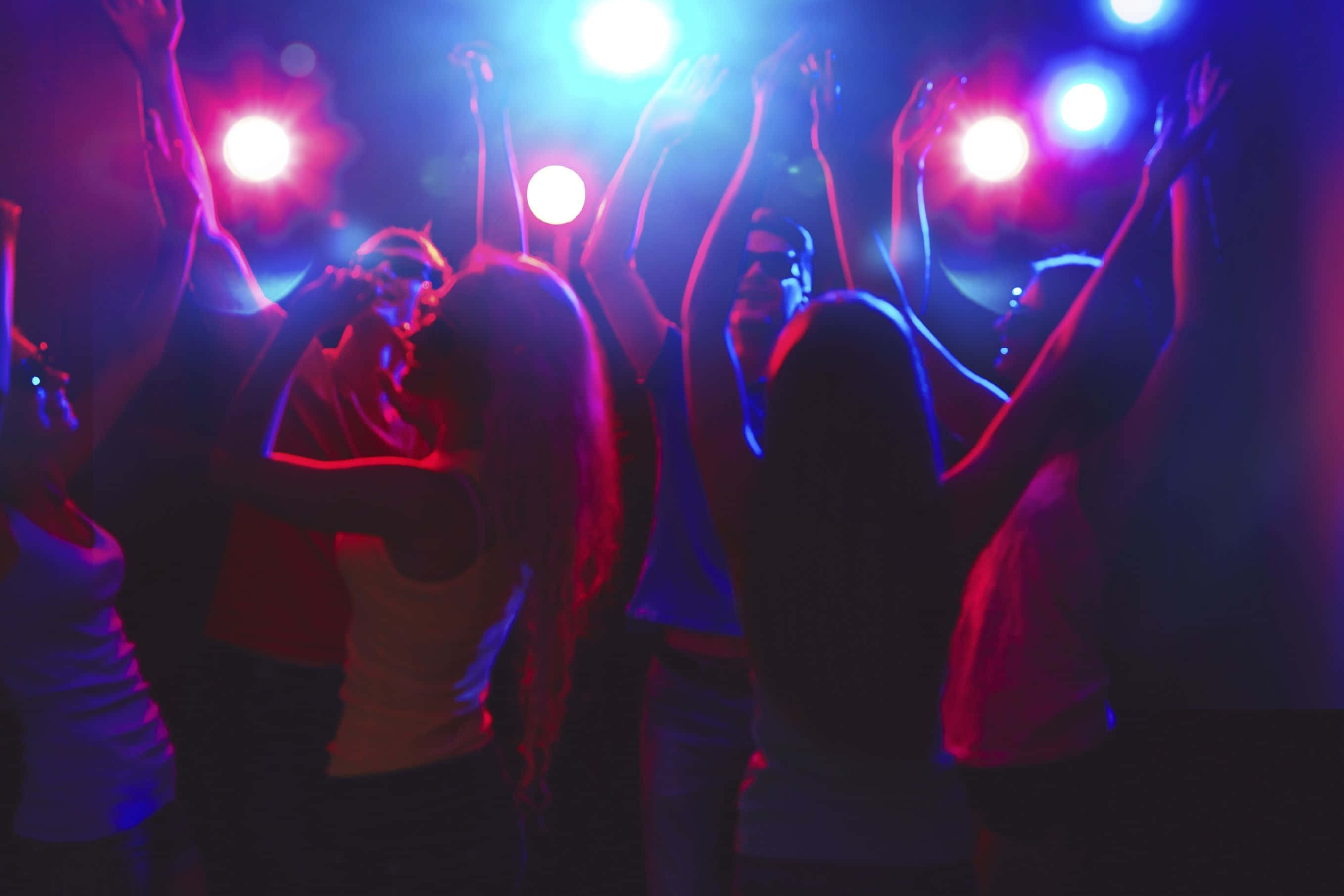 Nightclub 桌布 壁紙 — 人們在閃爍的紅藍色俱樂部燈光下狂喜地跳舞，高舉雙臂慶祝。