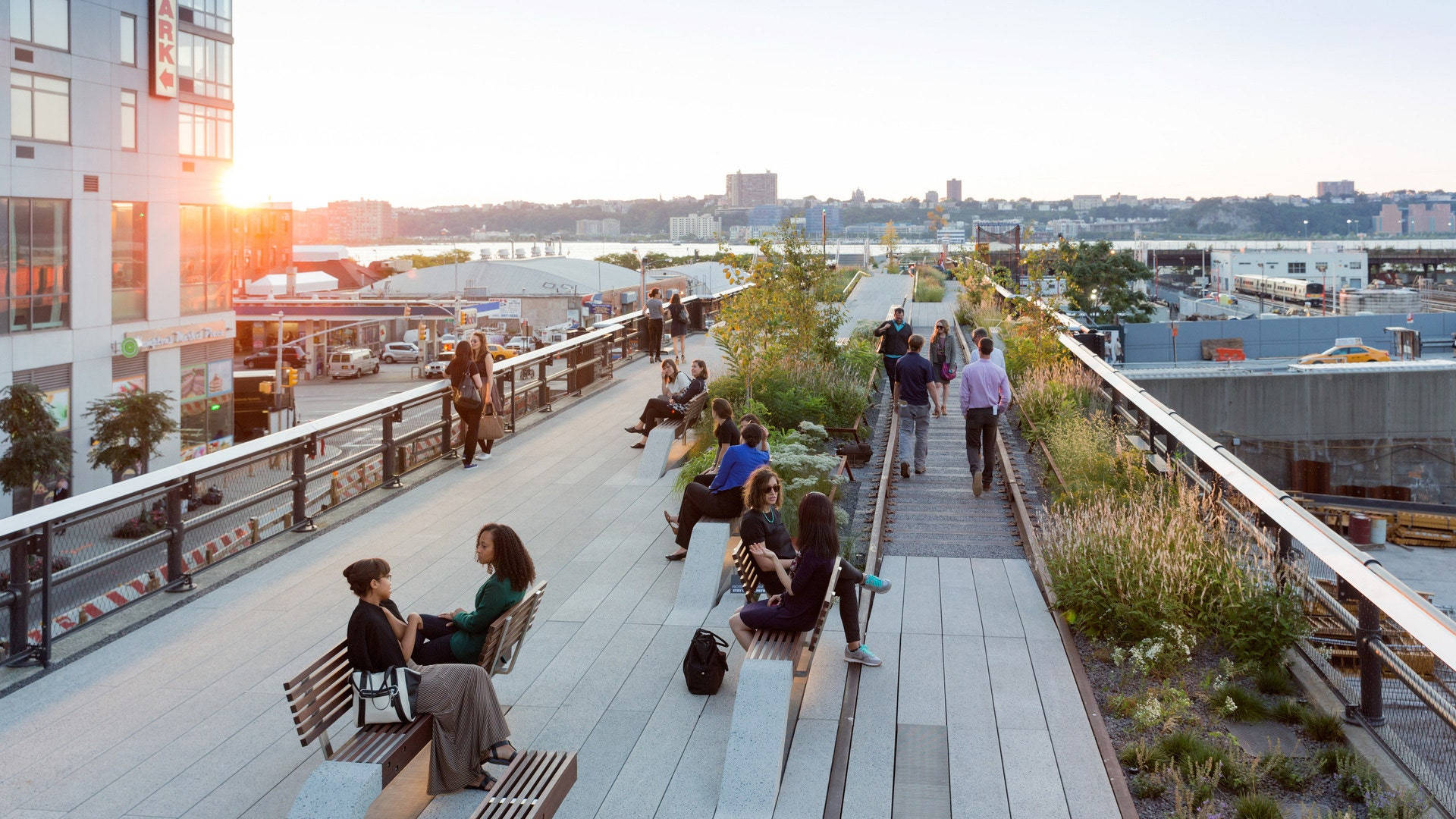 New York 桌布 壁紙 — 人們在高架的城市公園中放鬆和漫步，背景是城市景觀和水域，陽光普照。