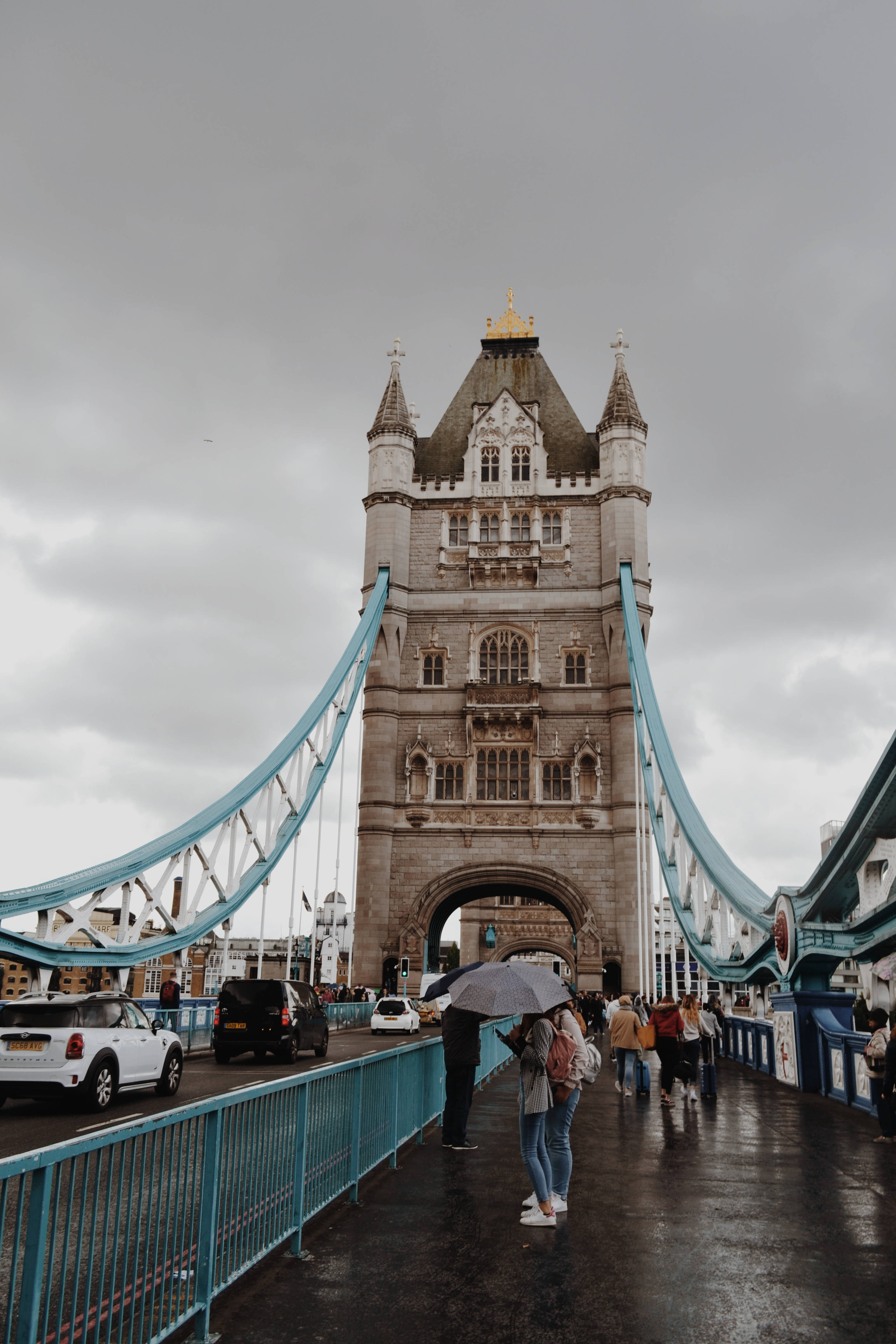 bridge 桌布 壁紙 — 人們撐著雨傘在灰濛濛的天空下走過倫敦塔橋，汽車在濕漉漉的道路上行駛。