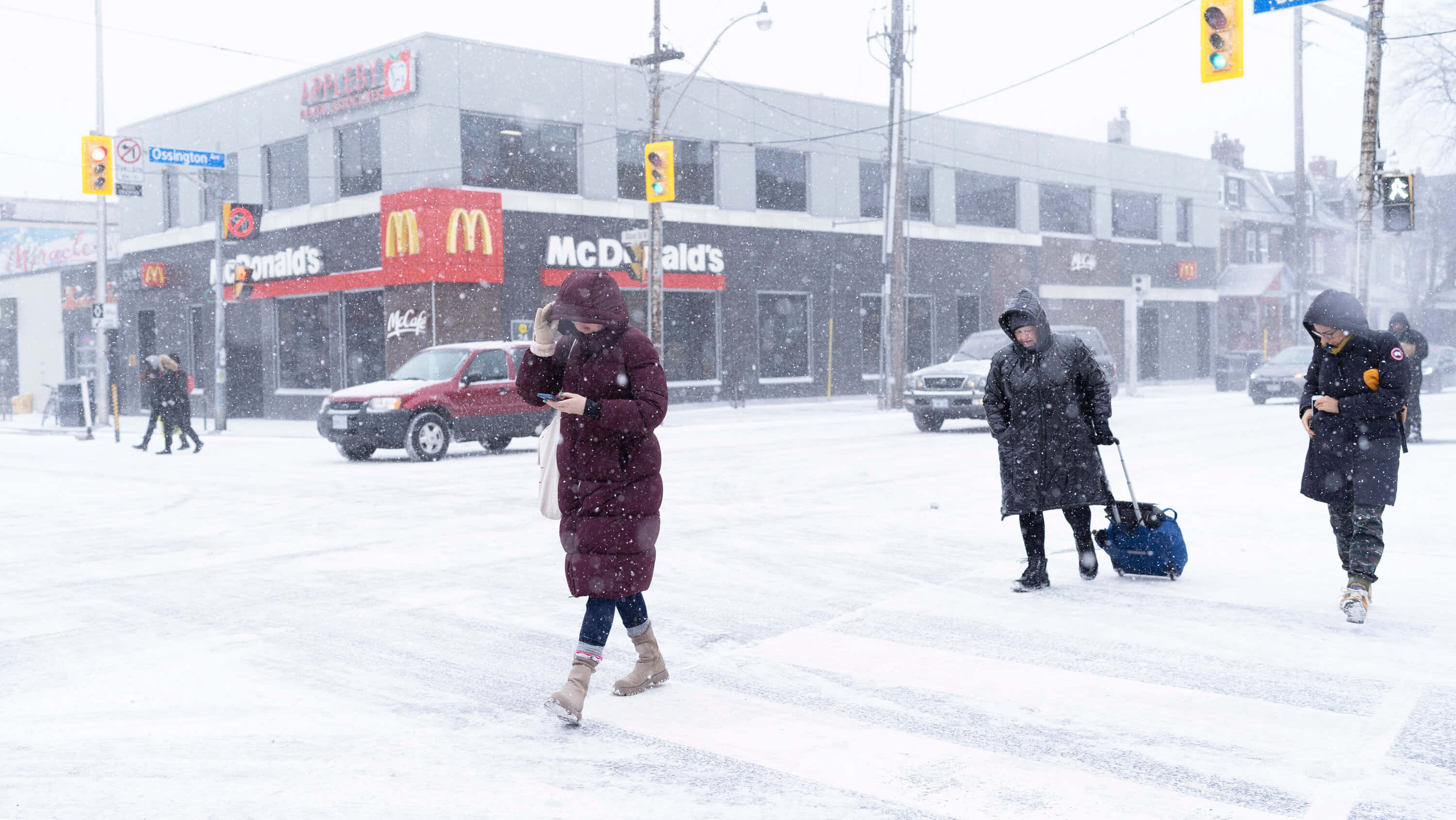 Winter 桌布 壁紙 — 人們穿著冬季外套在大雪中穿過麥當勞附近的積雪街道。