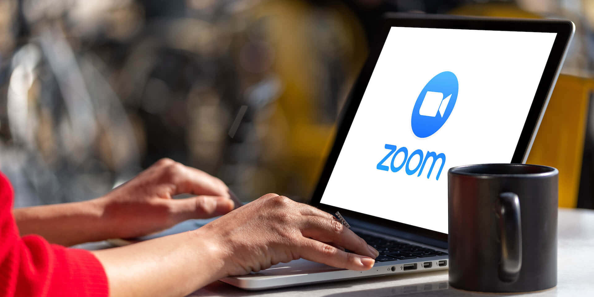人在戶外用Zoom筆記型電腦遠端工作，旁邊有咖啡杯。 — 放大 壁紙