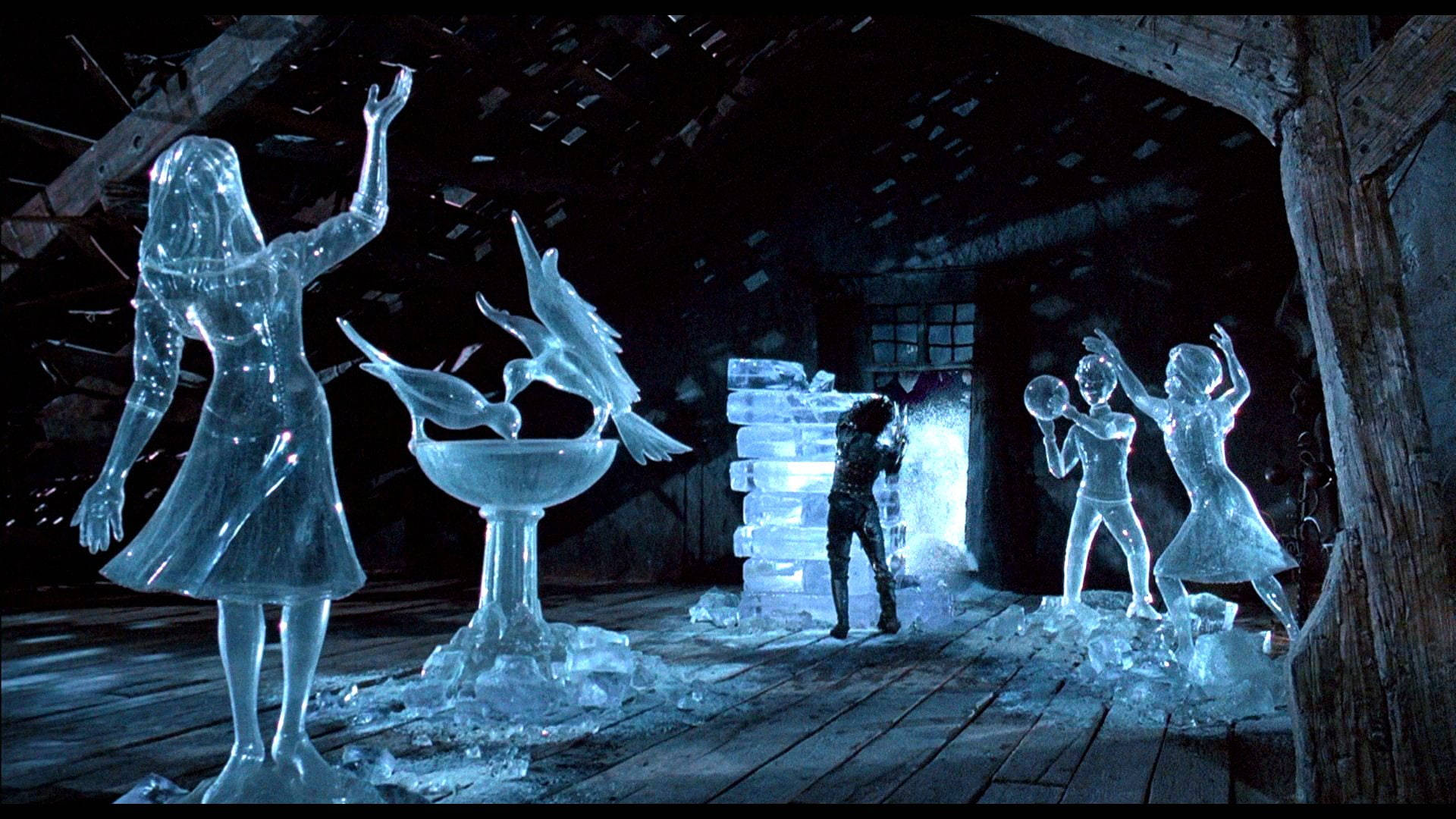 Edward Scissorhands 桌布 壁紙 — 人物和鳥類的冰雕在黑暗的木製閣樓中發出藍光，周圍雪花飄落。
