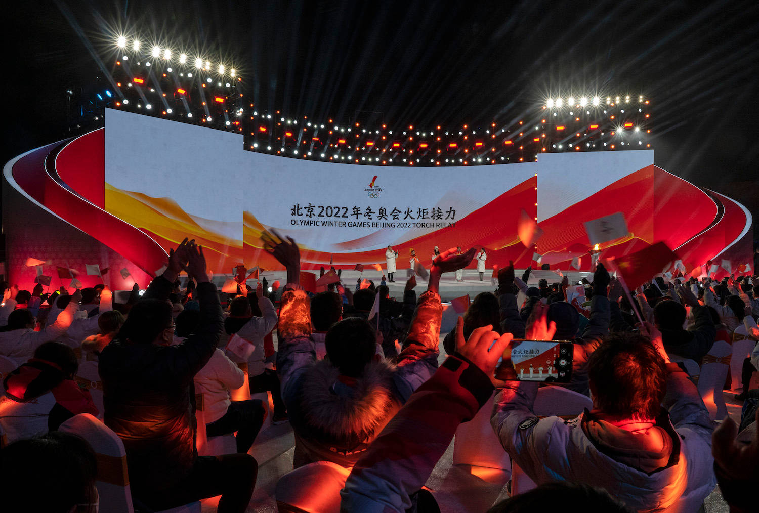 Winter Olympics 桌布 壁紙 — 人群在北京2022年冬季奧運火炬傳遞活動中，在明亮的體育場燈光下歡呼。