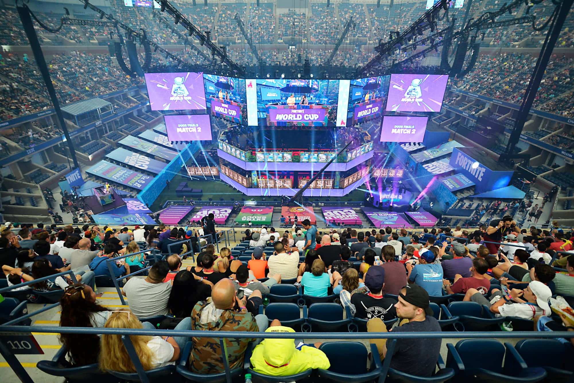 Gaming Conventions 桌布 壁紙 — 人群在擠滿的場館中，於明亮的舞台燈光下觀看Fortnite World Cup電競錦標賽。