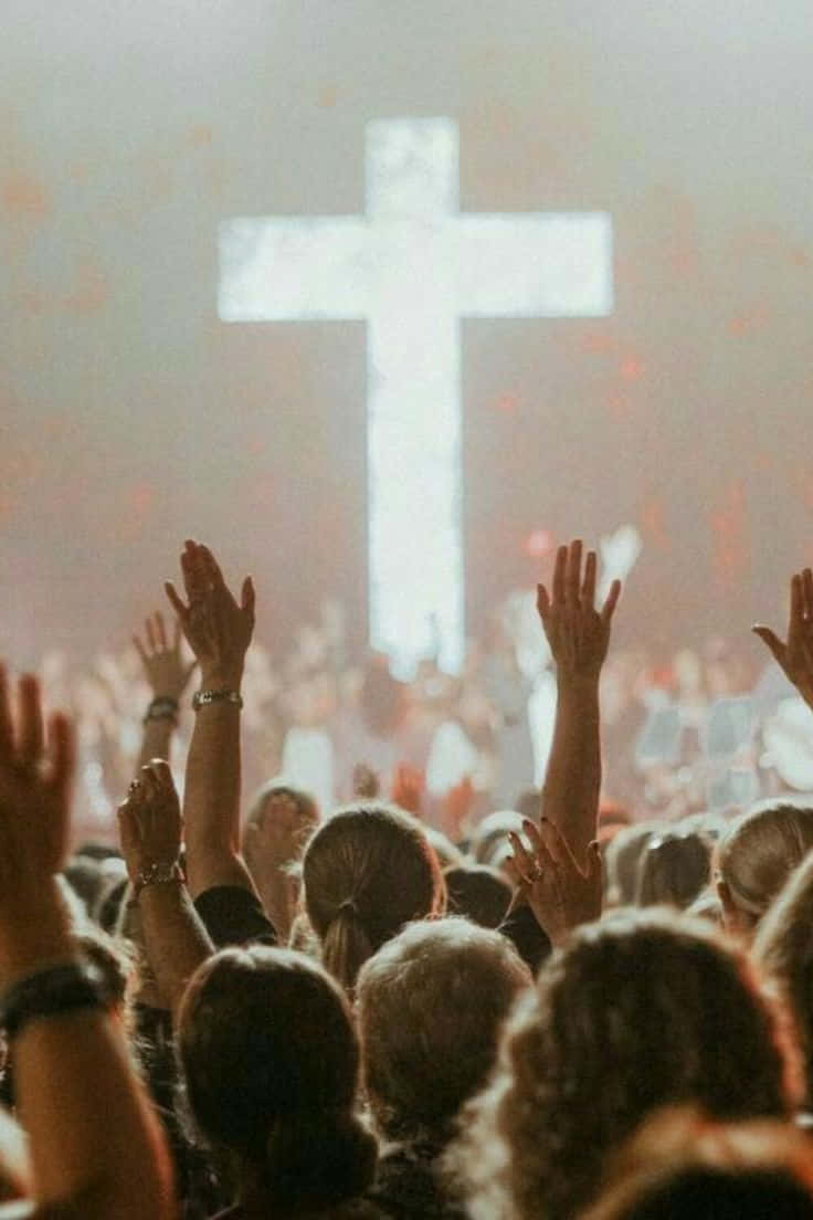 Worship 桌布 壁紙 — 人群在溫暖光線籠罩的朦朧崇拜中，向發光的十字架舉起雙手。