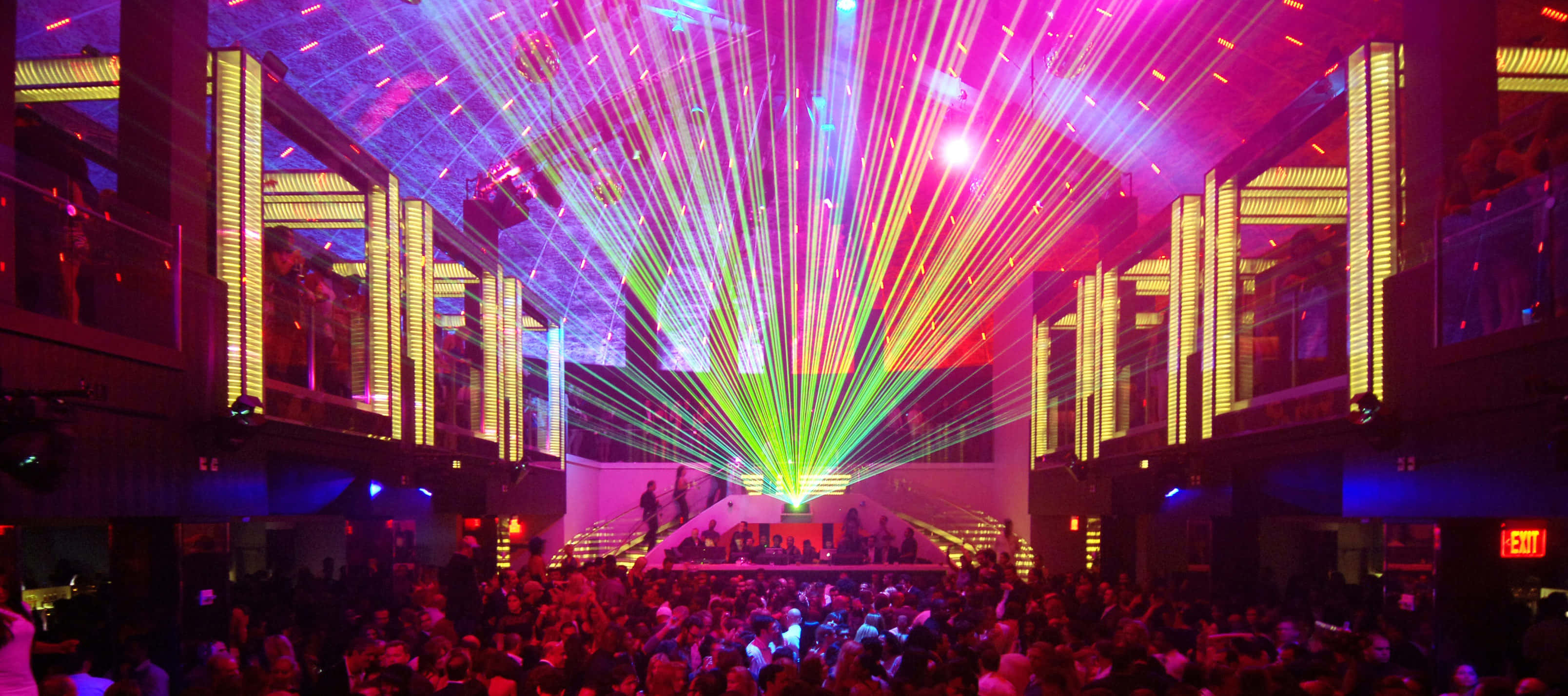 Nightclub 桌布 壁紙 — 人群在漆黑的夜店中，於粉紅、綠色和黃色雷射光束的耀眼展示下跳舞。