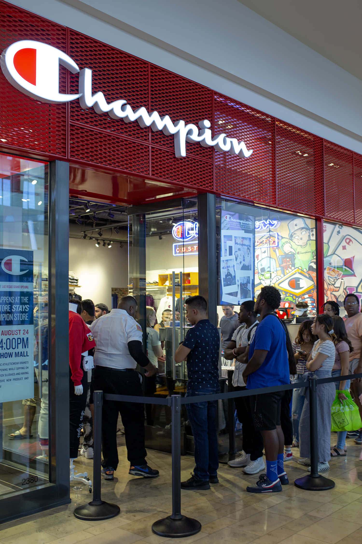 Champion 桌布 壁紙 — 人群在購物中心內一間亮紅色Champion商店外排隊，商店有玻璃門，牆上佈滿色彩繽紛的塗鴉藝術。