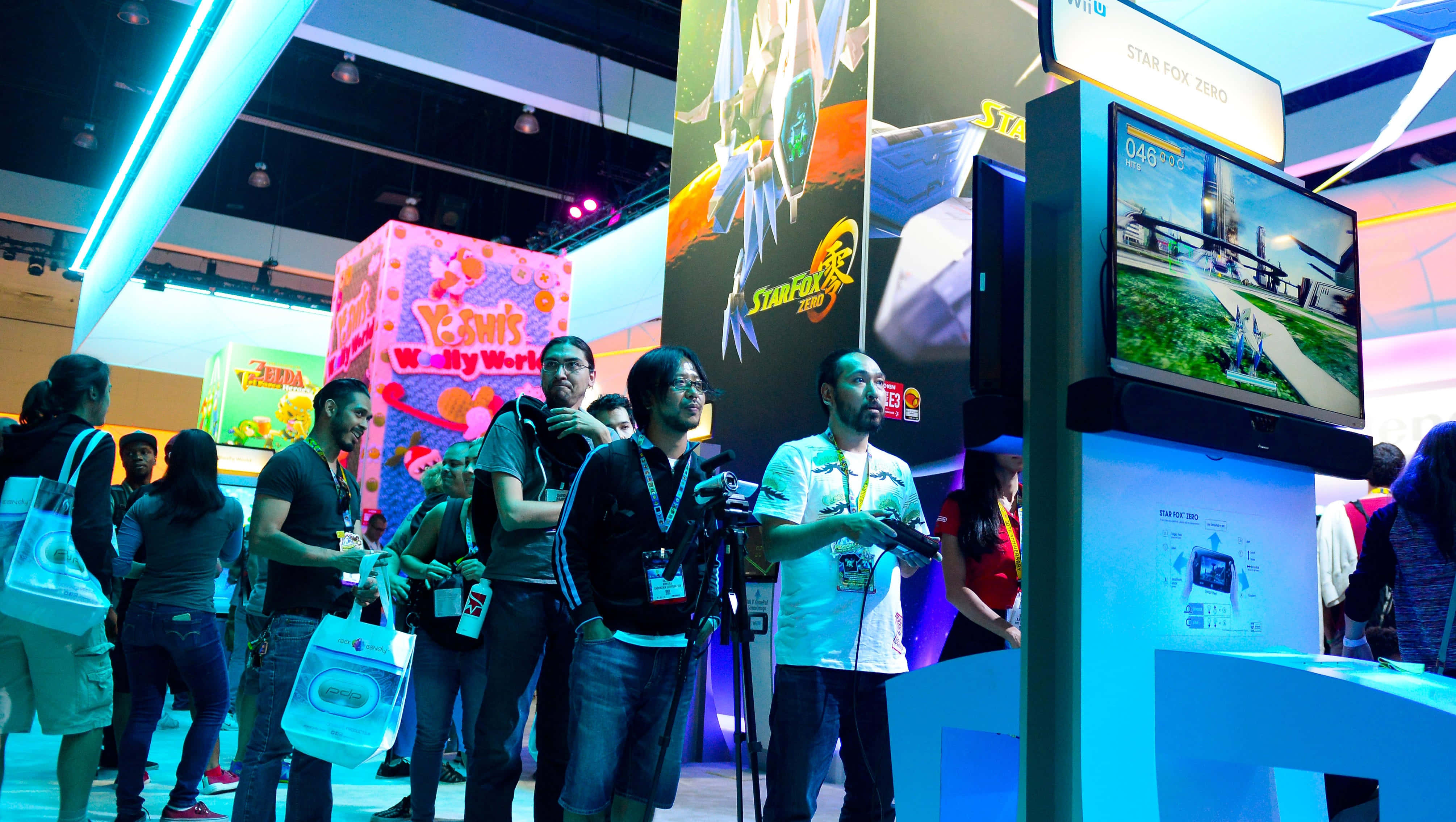 Gaming Conventions 桌布 壁紙 — 人群聚集在一個光線明亮的會議廳內，圍繞著Star Fox Zero遊戲站，周圍有色彩繽紛的攤位和發光的標誌。