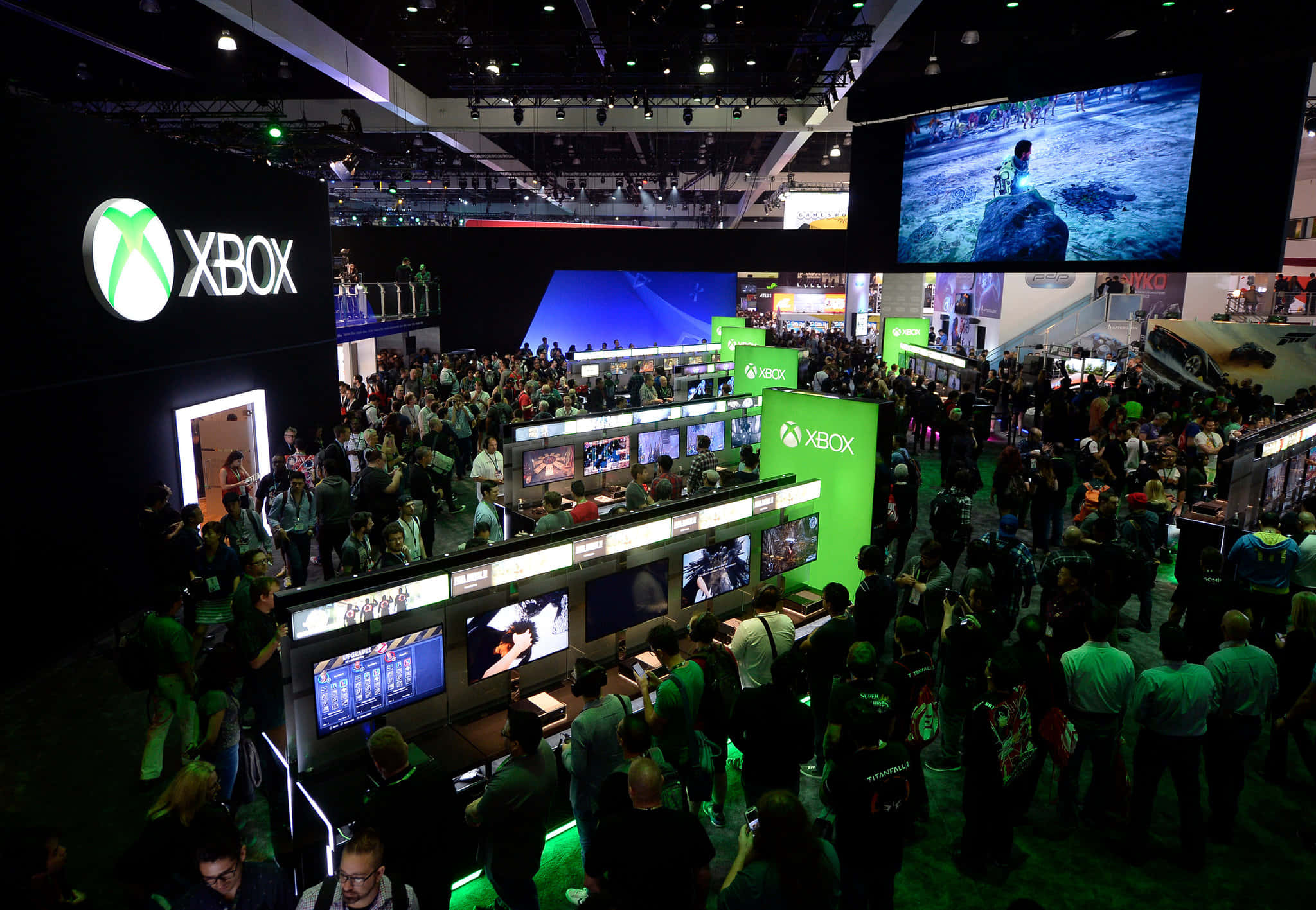 Gaming Conventions 桌布 壁紙 — 人群聚集在發光綠色燈光下的Xbox遊戲站周圍，在繁忙的會議廳中。