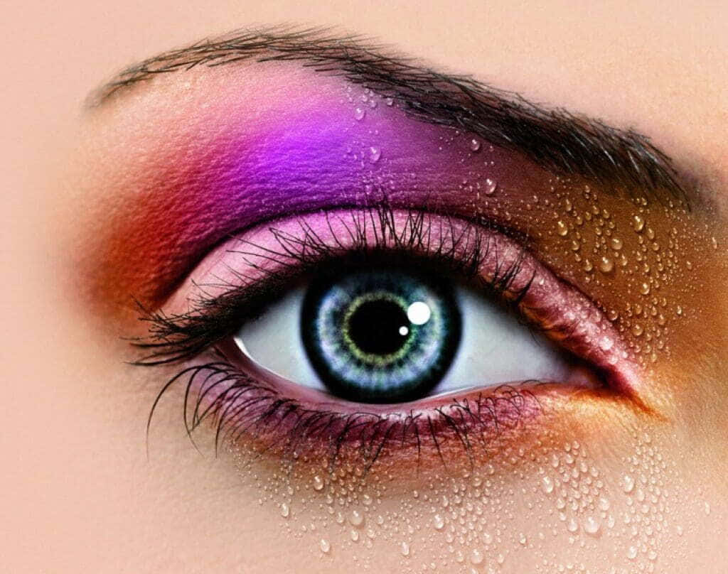 Purple Eye Shadow 桌布 壁紙 — 人類眼睛的特寫，帶有充滿活力的紫色和橙色眼影，以及在眼瞼和皮膚上閃閃發光的水滴。