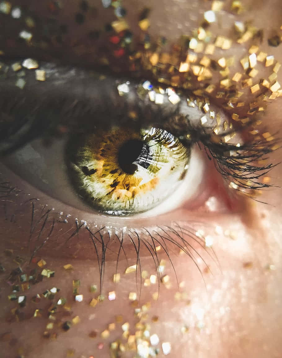Eyelashes 桌布 壁紙 — 人類眼睛的特寫，金色亮粉散佈在眼瞼和皮膚上。