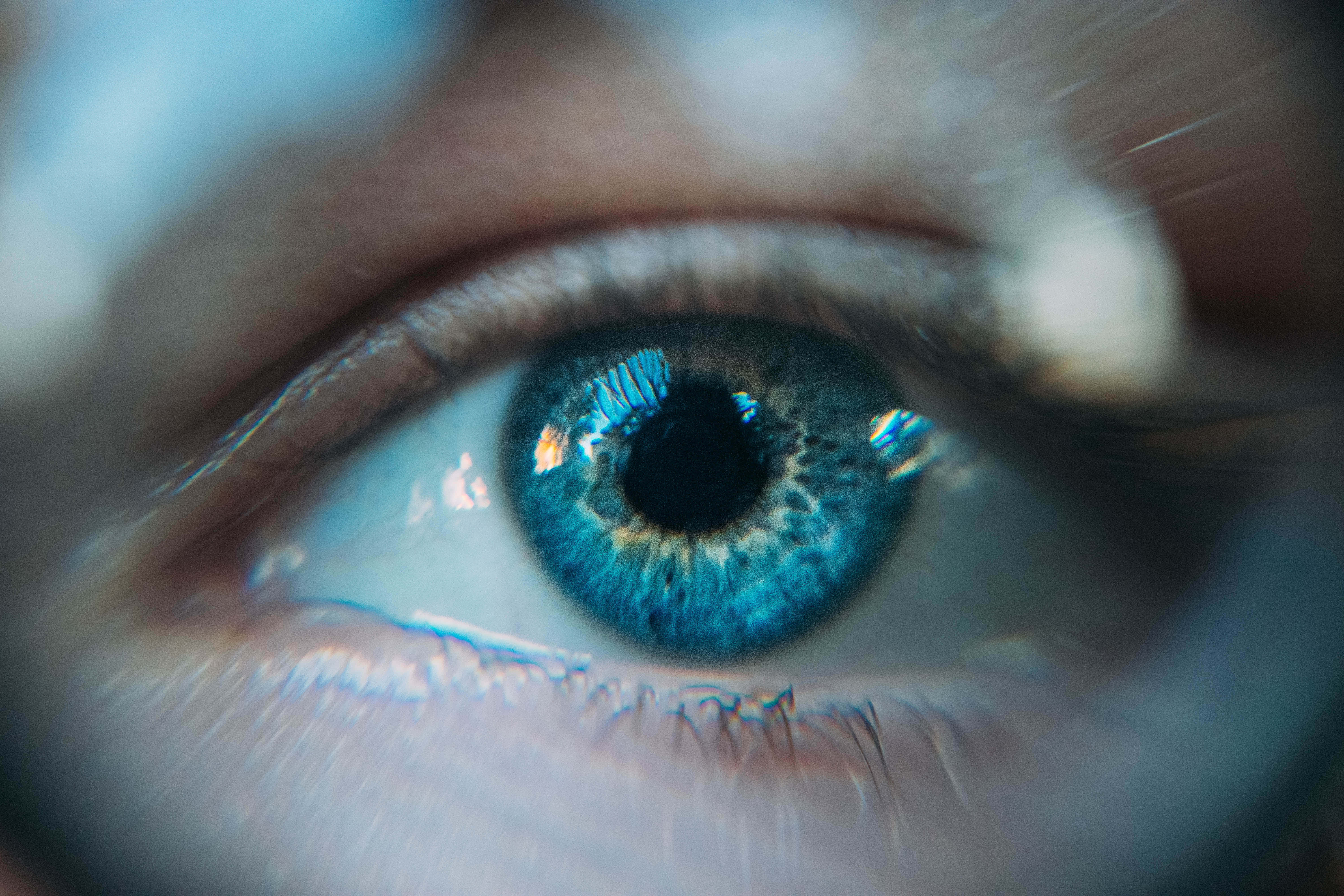 Eyes 桌布 壁紙 — 人類眼睛的超現實特寫，具有鮮豔的藍色虹膜，並對被模糊皮膚和睫毛包圍的瞳孔進行銳利對焦。