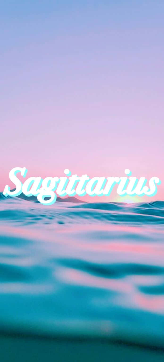 Sagittarius Aesthetic 桌布 壁紙 — 人馬座文字在粉彩粉紅和藍色的暮色天空下，在平靜的海浪上發光。