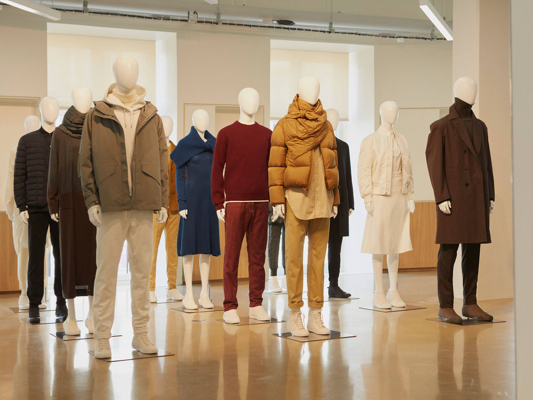 Mens Fashion 桌布 壁紙 — 人體模型在一個極簡主義的零售空間中展示秋冬時尚，配有溫暖的燈光和拋光地板。