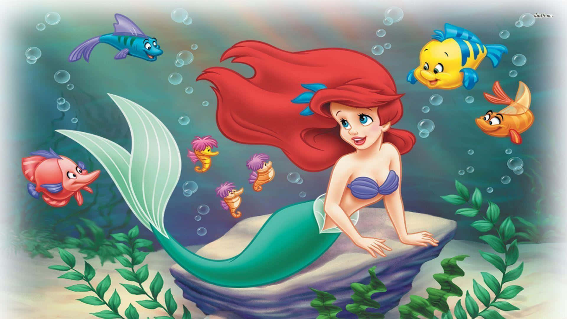 The Little Mermaid 桌布 壁紙 — 人魚公主艾莉兒擁有一頭飄逸的紅髮，坐在岩石上，周圍是色彩繽紛的魚類和氣泡，構成一個海底場景。