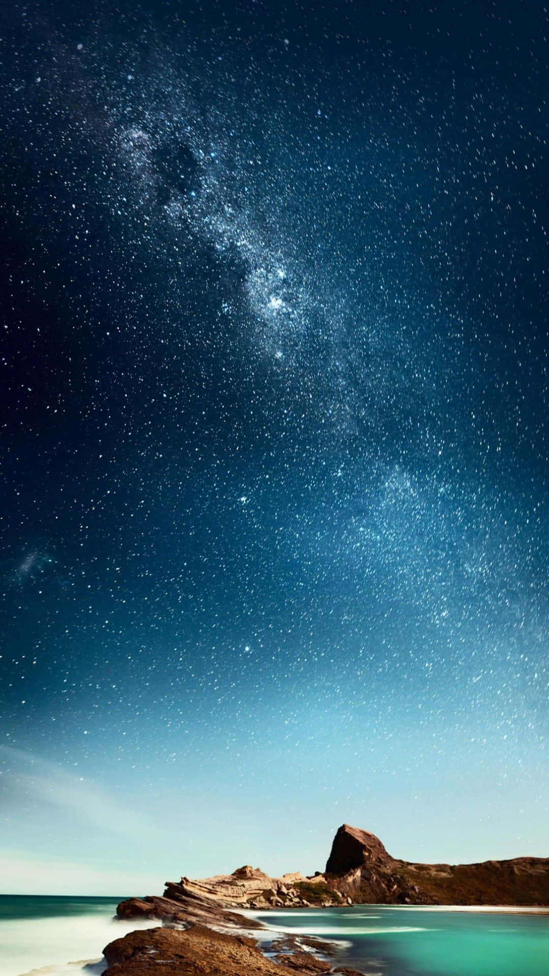 桌布 壁紙 — 令人嘆為觀止的夜空，佈滿無數星星，銀河在平靜的碧綠海洋和岩石海岸線上拱起。