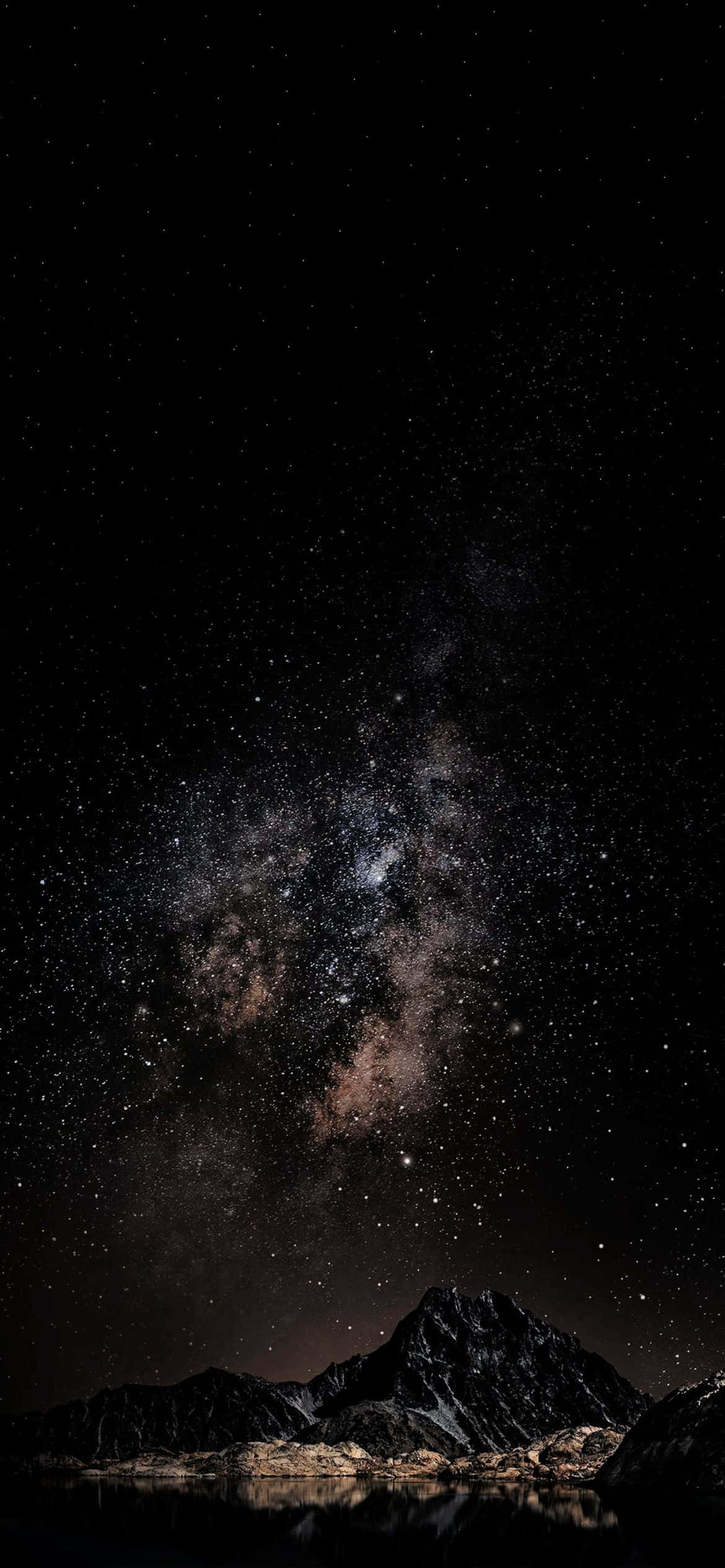 iPhone 12 Pro 桌布 壁紙 — 令人嘆為觀止的夜空，佈滿繁星和銀河，拱形橫跨在倒映於平靜水面上的黑暗山脈之上。