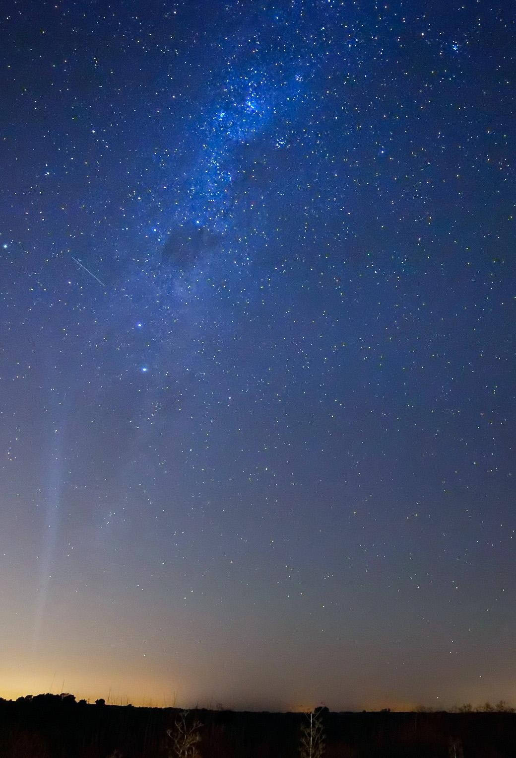 Stars 桌布 壁紙 — 令人嘆為觀止的夜空，充滿無數星星和閃爍的銀河，在黑暗的剪影地平線上方拱起。